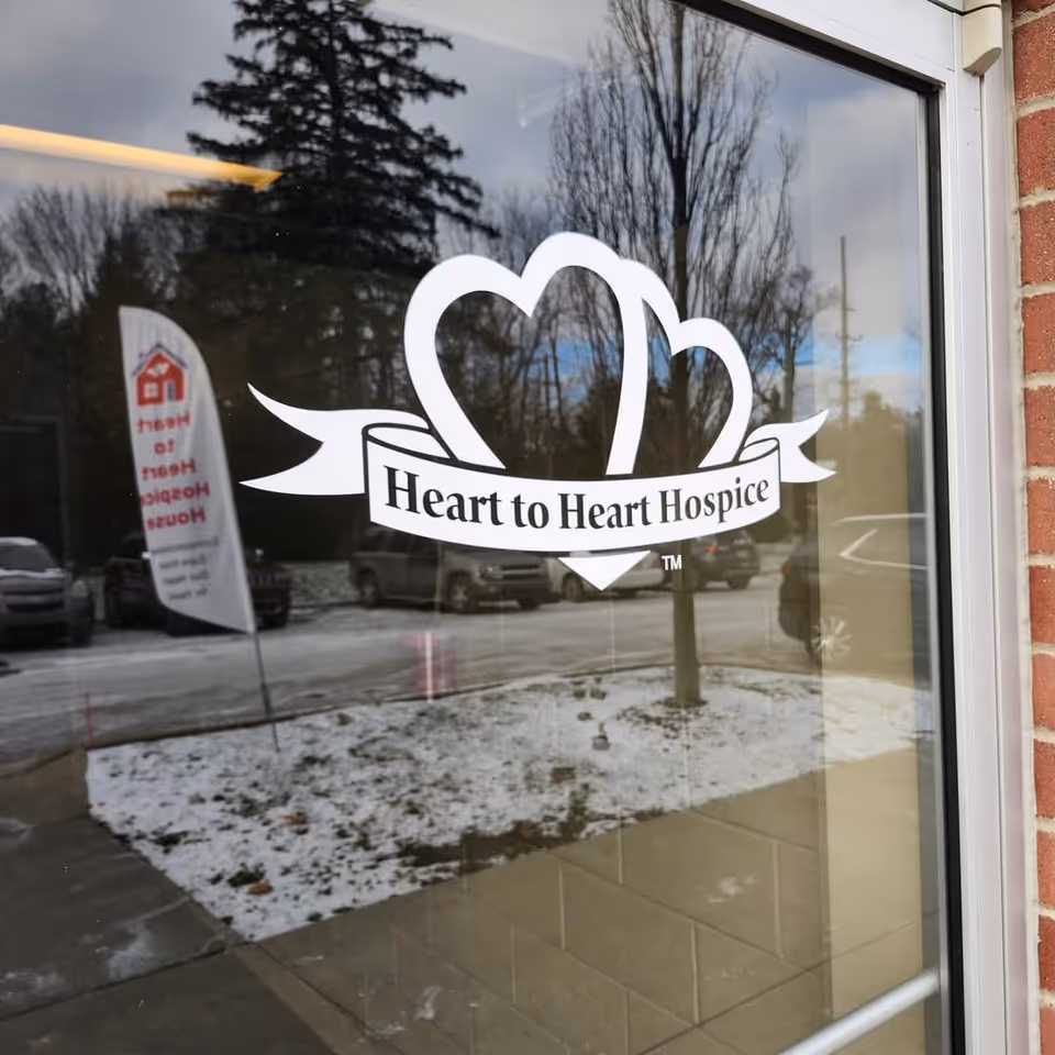 Window sign reads Heart to Heart Hospice House on brick building exterior.