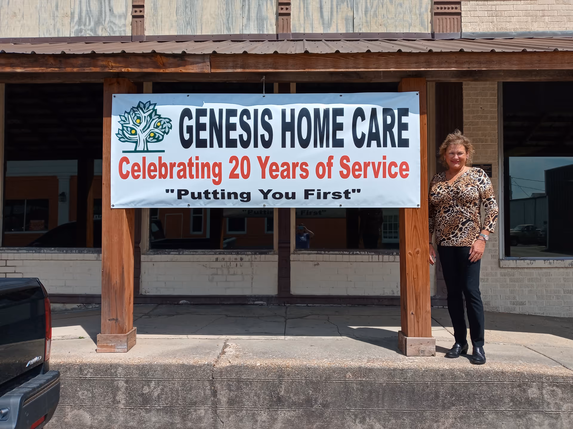 Exterior view of Genesis Home Care with a banner and a woman standing.