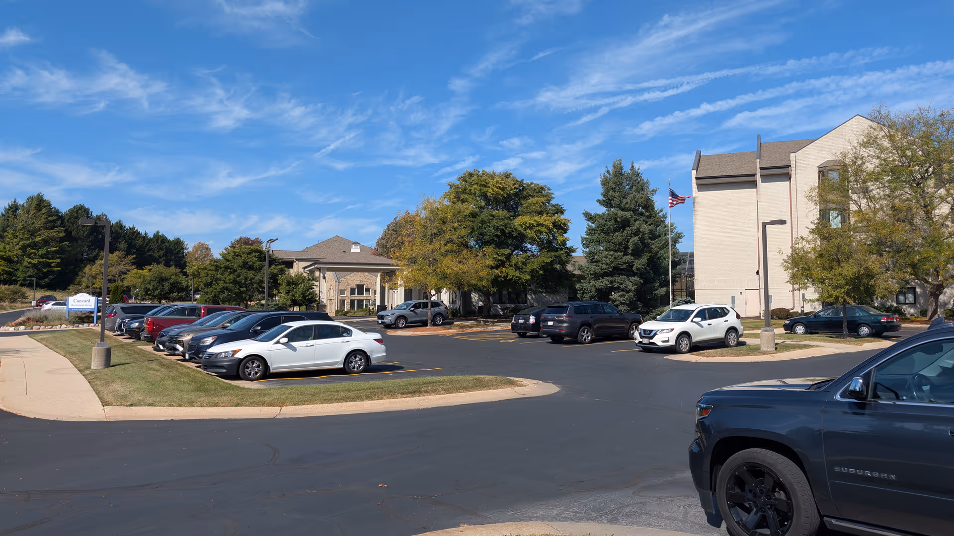 Exterior view of Harbour House senior living facility with a parking lot and trees.