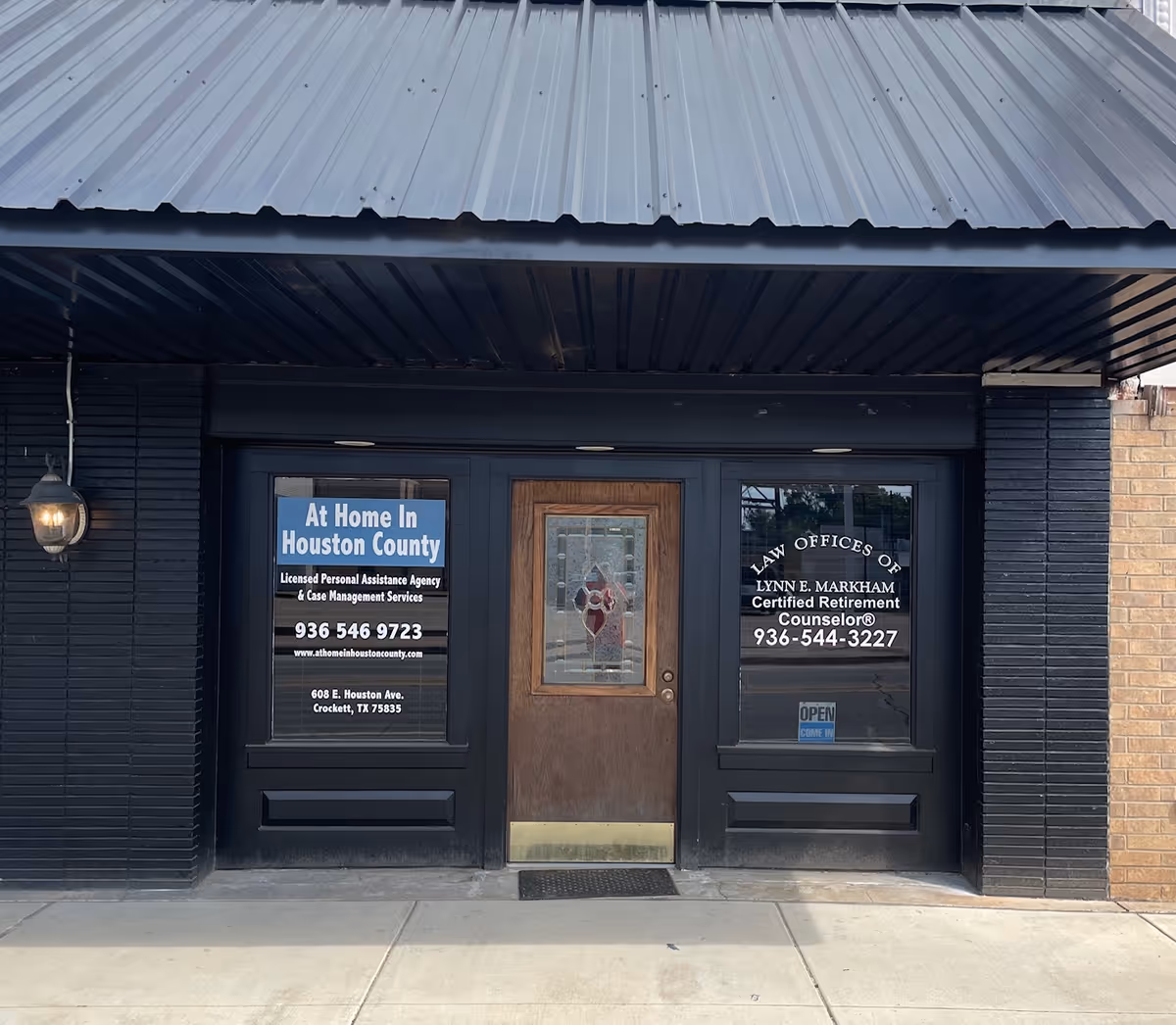 Dark exterior storefront featuring a central wooden door and signs for At Home in Houston County.