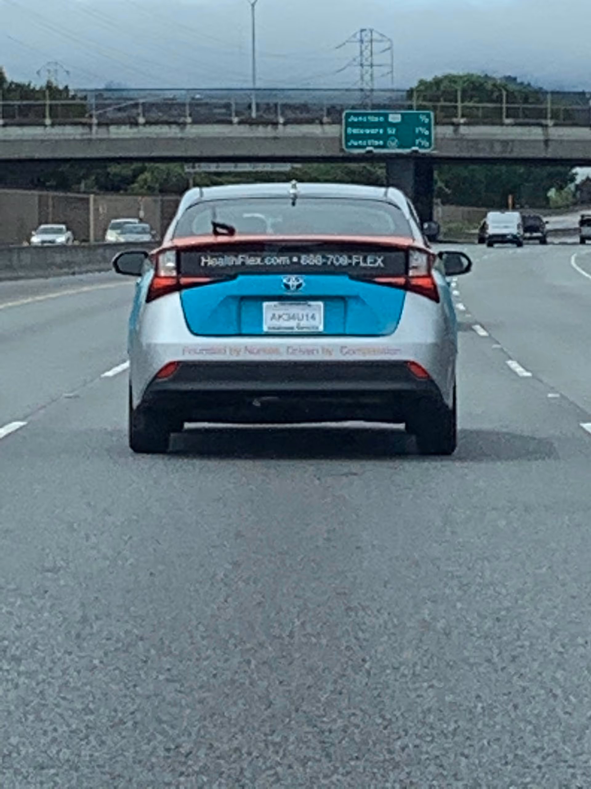 Rear view of a HealthFlex branded car driving on a highway.