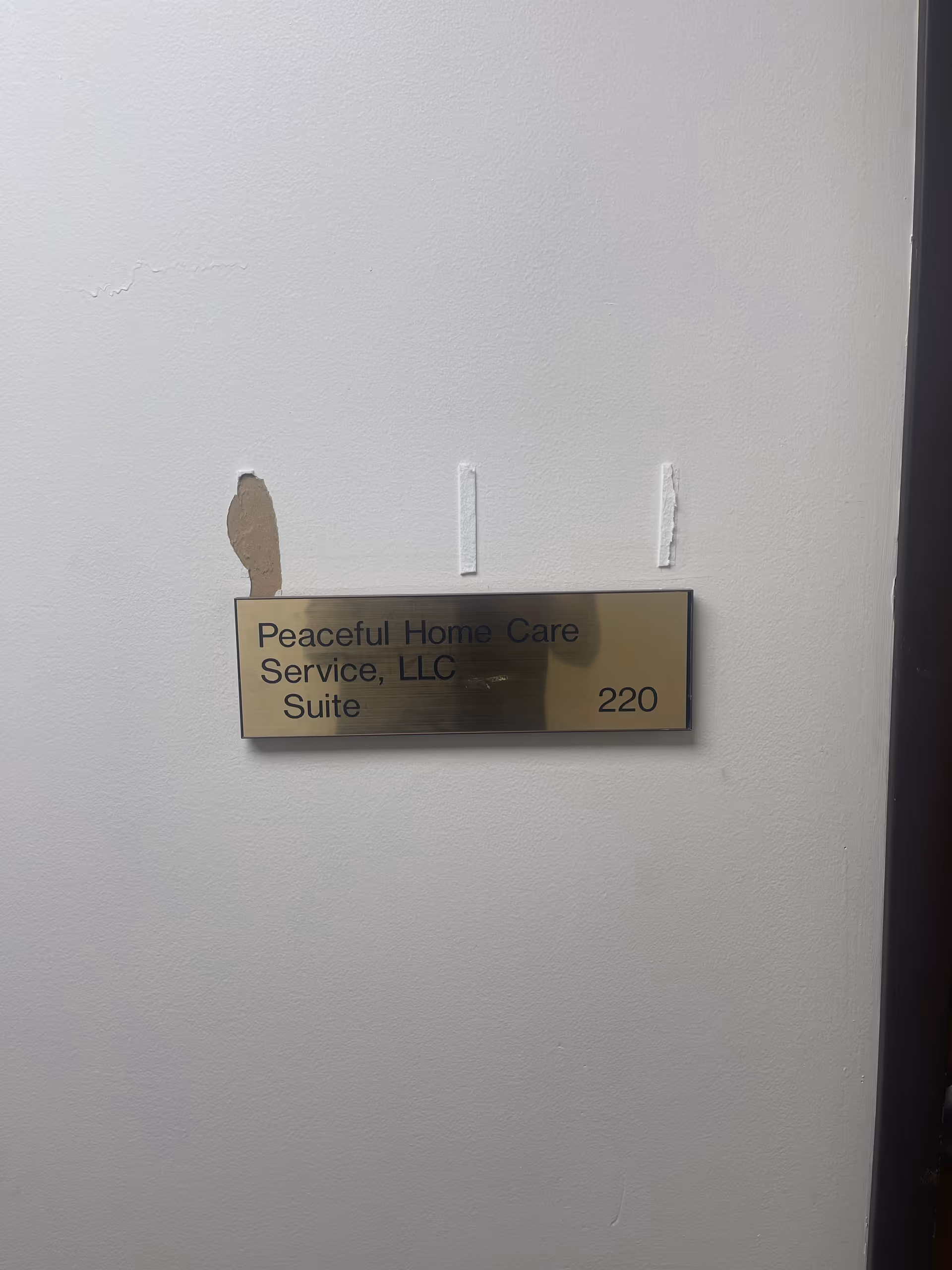 Gold plaque on a gray wall reads Peaceful Home Care Service, LLC Suite 220.