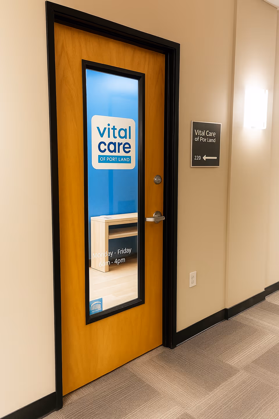 Wooden door with a glass panel showing the Vital Care of Portland sign in a hallway.