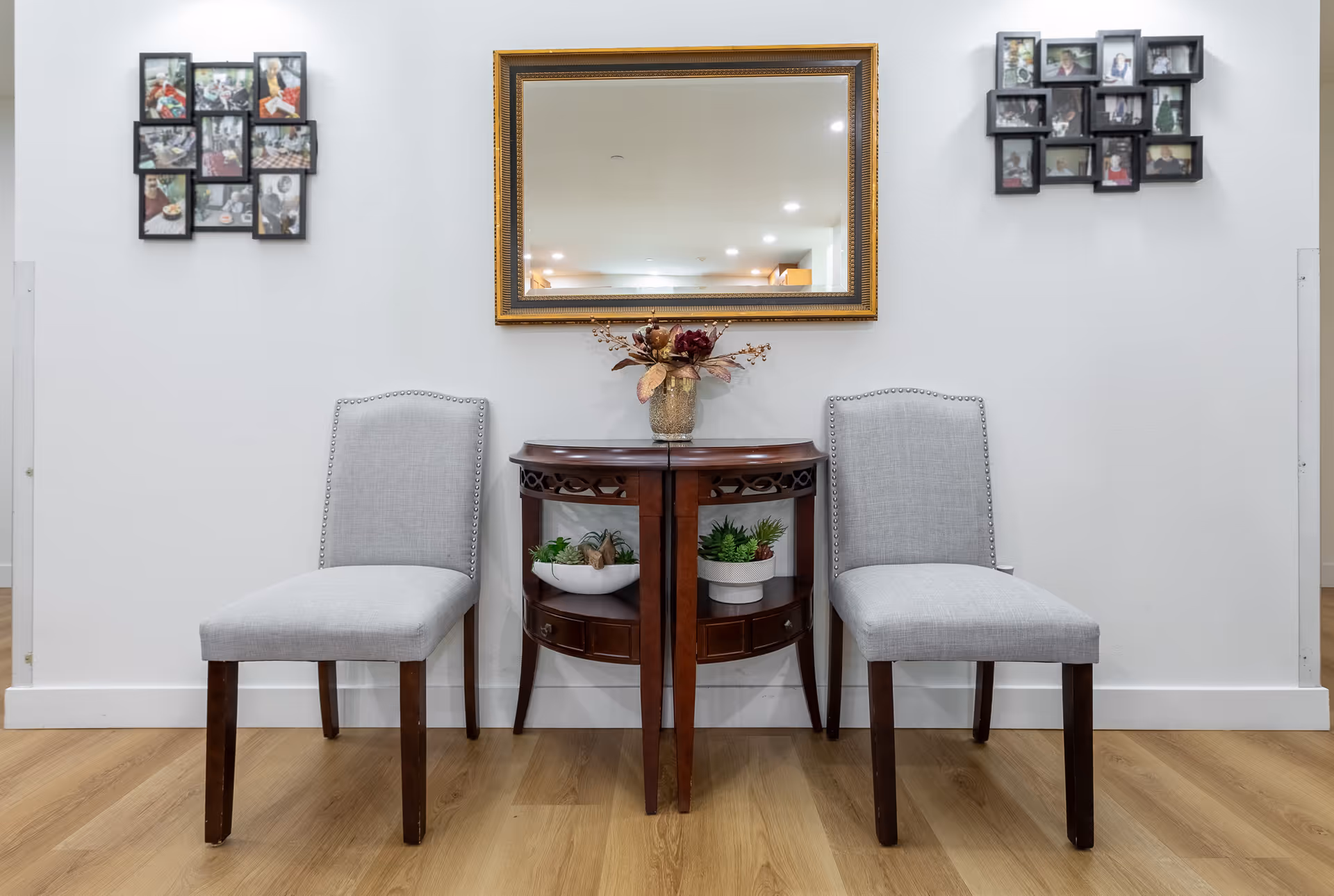 Two gray upholstered chairs flank a wooden console table with a framed mirror.