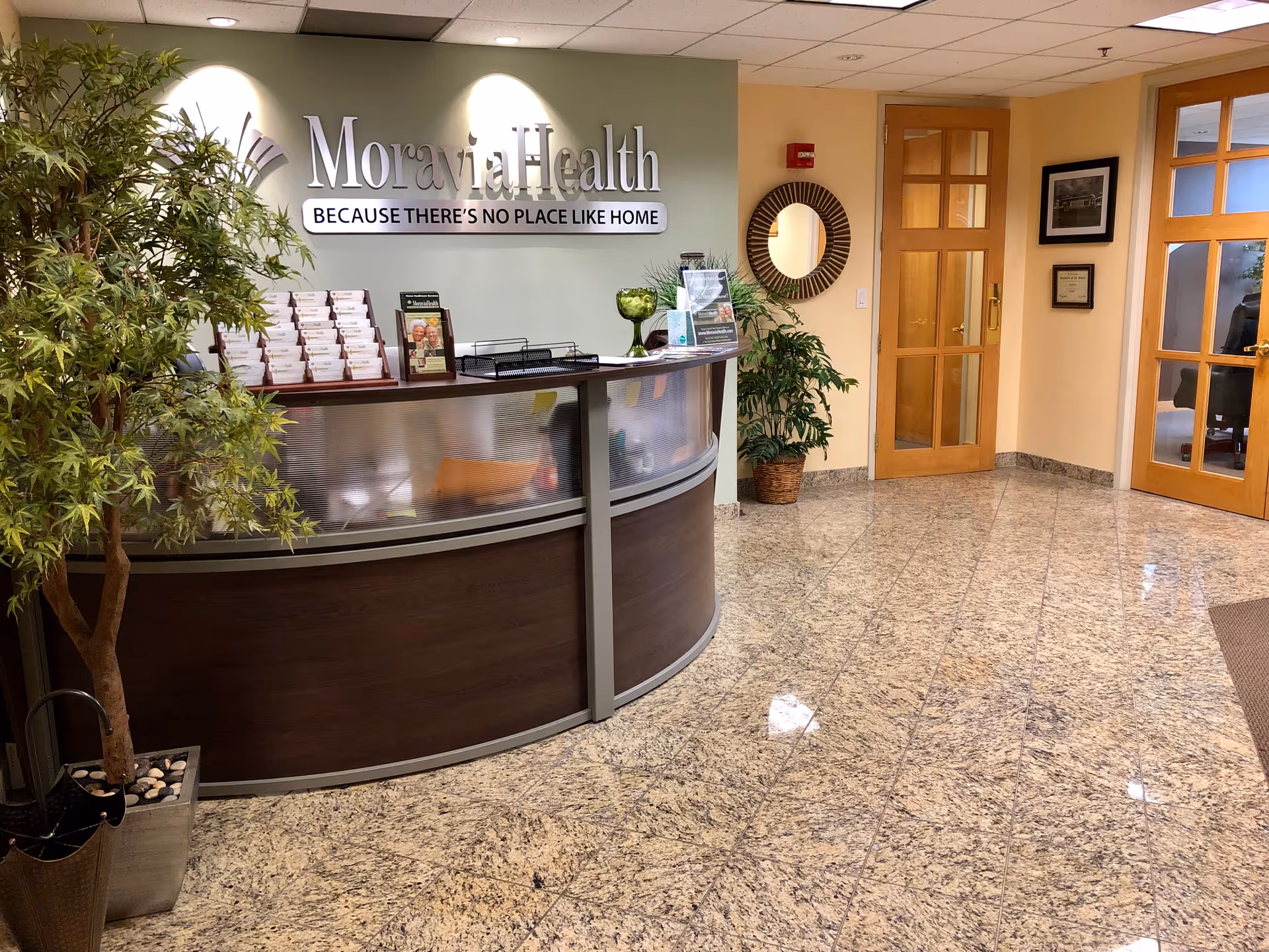 Reception desk in Moravia Health lobby with plants and a curved counter.