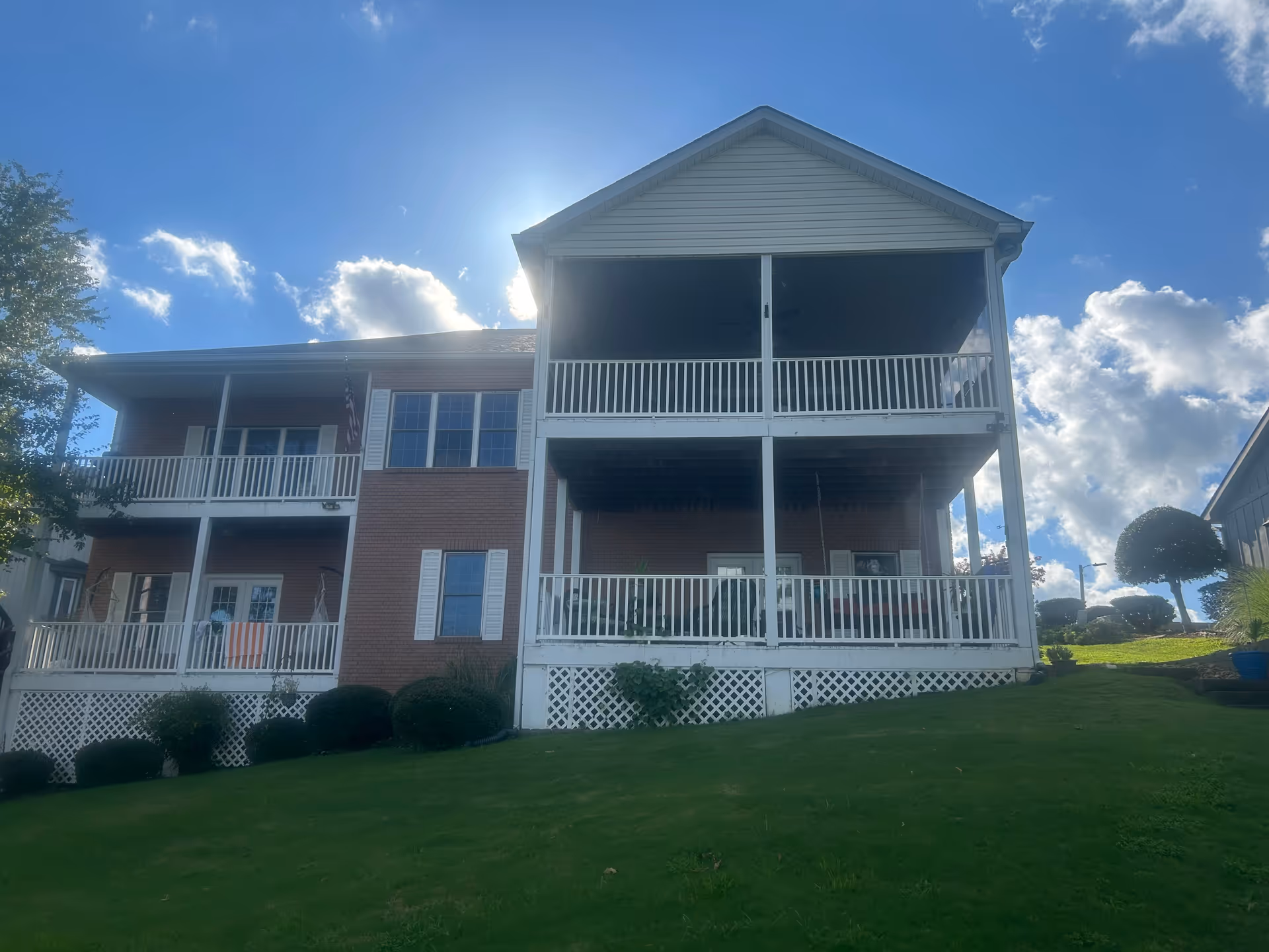 A multi-story senior living building with white railings and balconies on a grassy lawn.