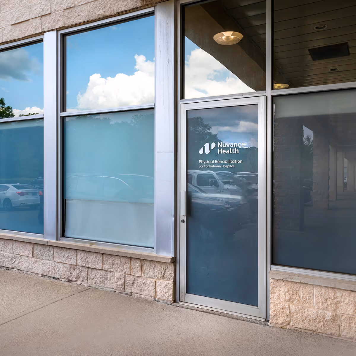 Glass storefront of Nuvance Health Physical Rehabilitation at Katonah with car reflections.