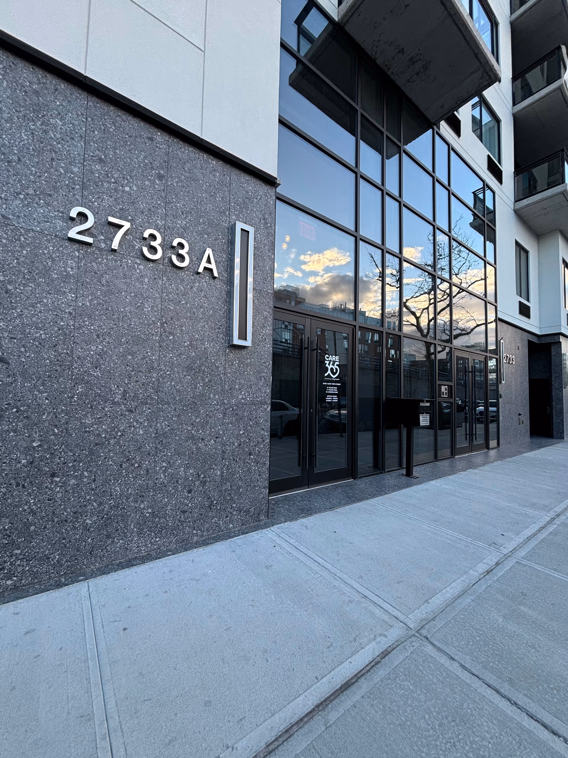 Modern glass-front building entrance with large numbers 2733A and Care365 logo on door.