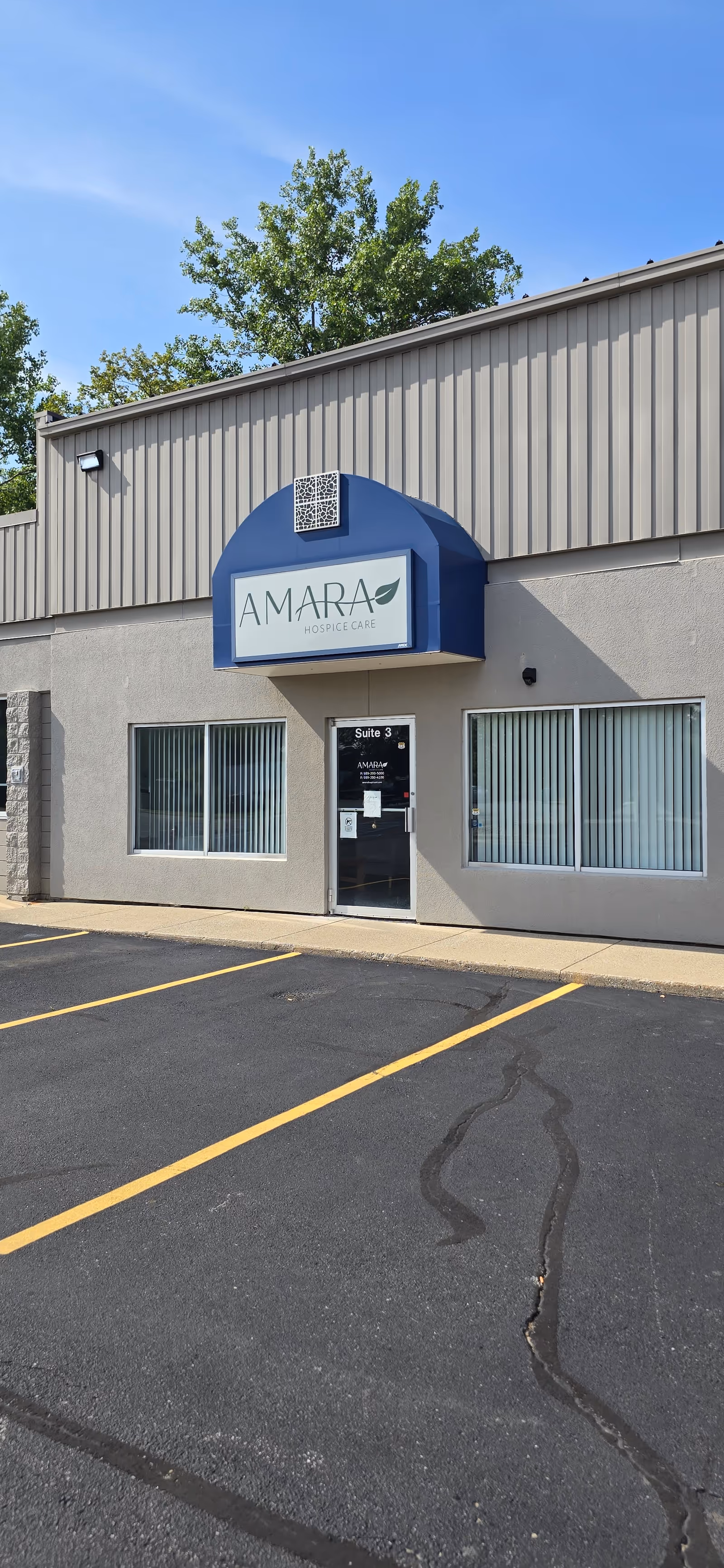 Exterior view of Amara Hospice Care building with blue entrance canopy and parking lot.