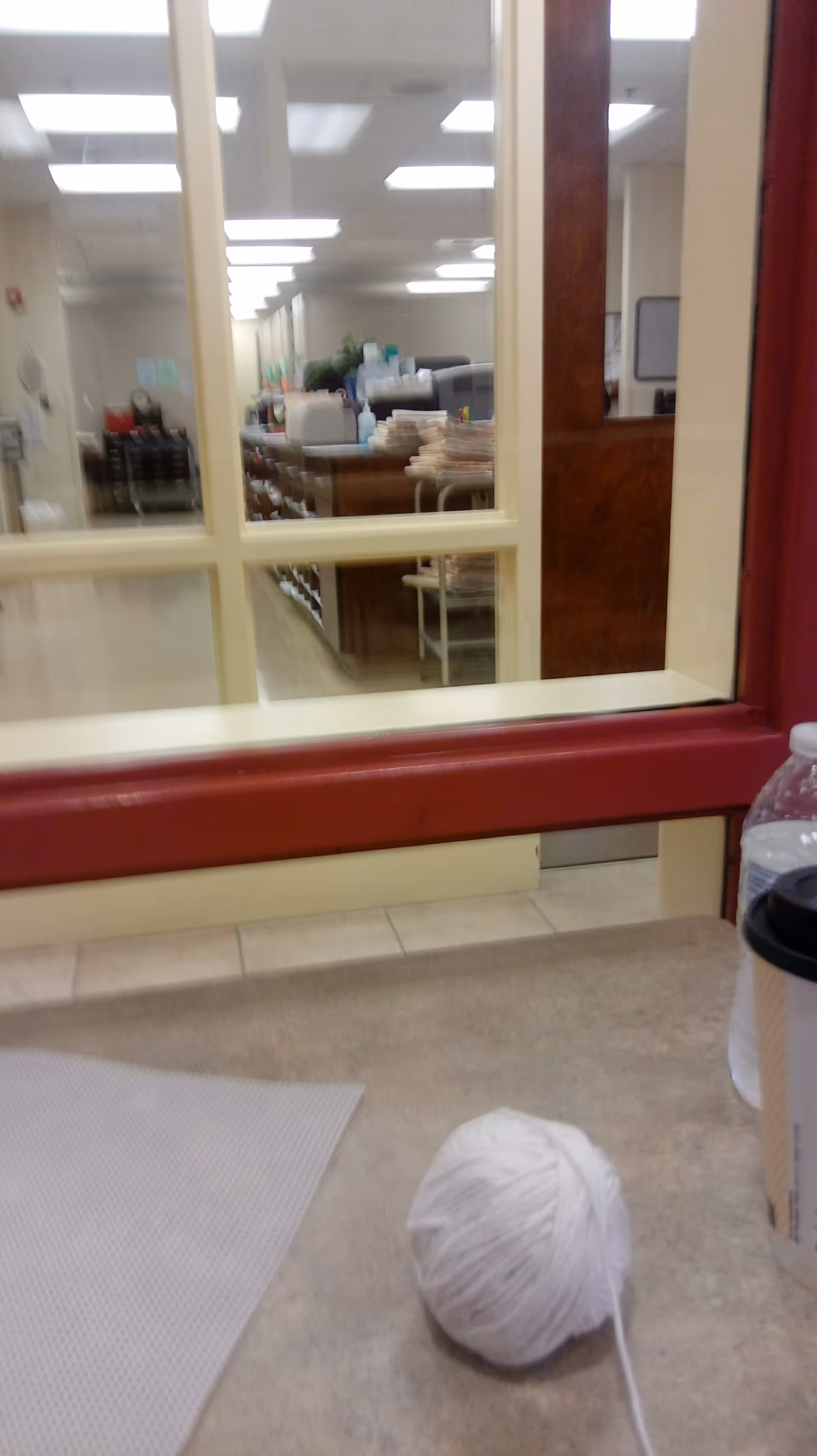 Interior scene through a service window into a desk area with papers.