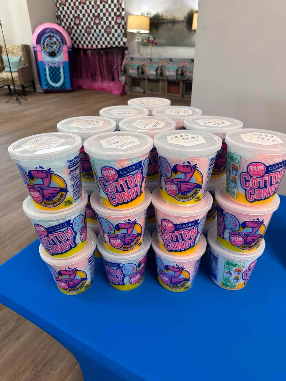 Stacked cotton candy containers on a blue table in a bright interior room.