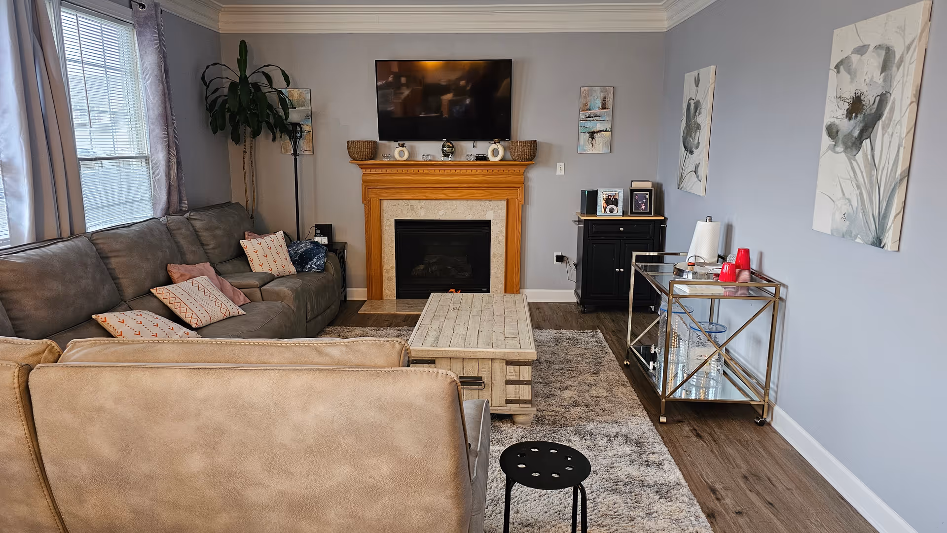 Cozy living room with gray couches, fireplace, TV, coffee table, and wall art.