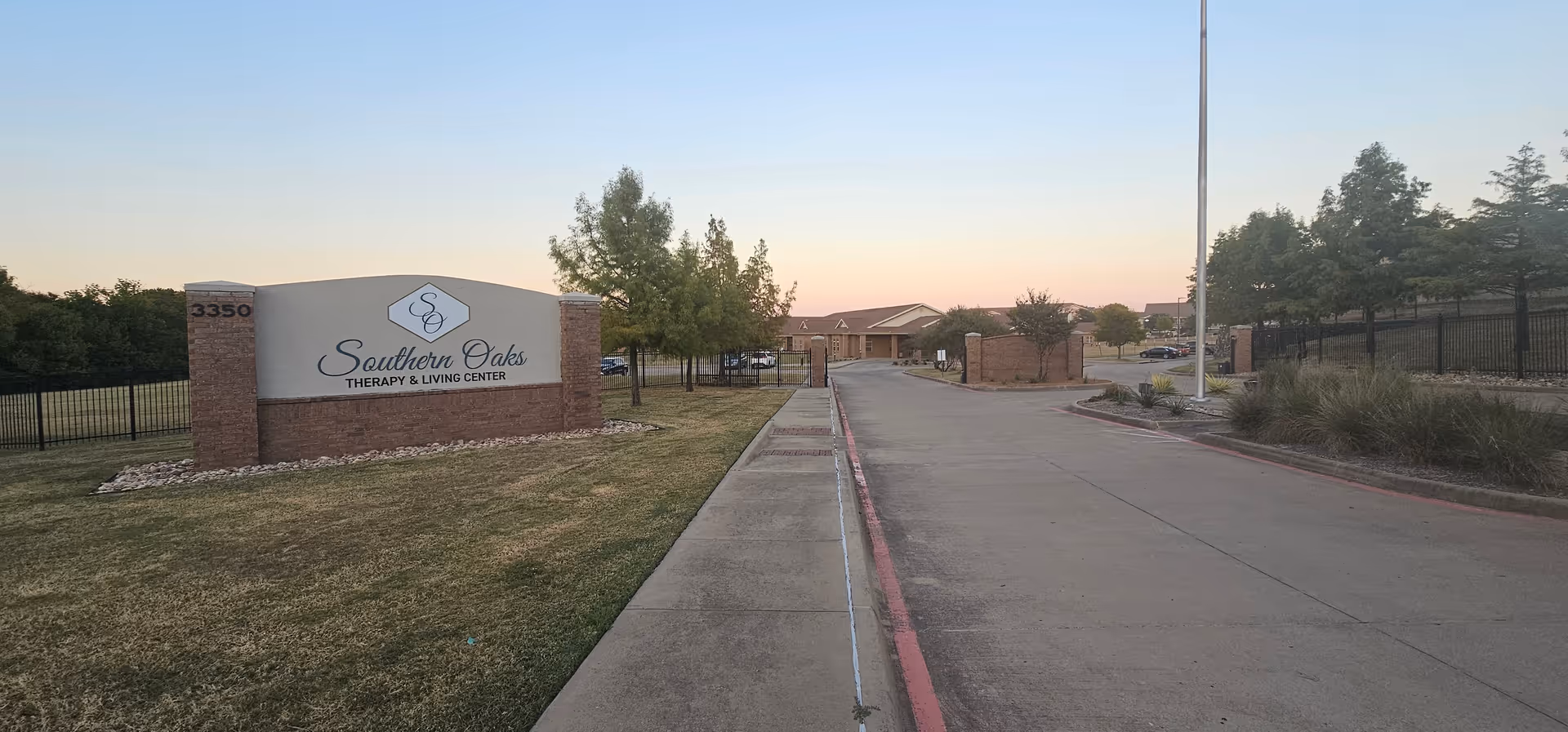 Exterior view of a senior living facility entrance with a sign and driveway.