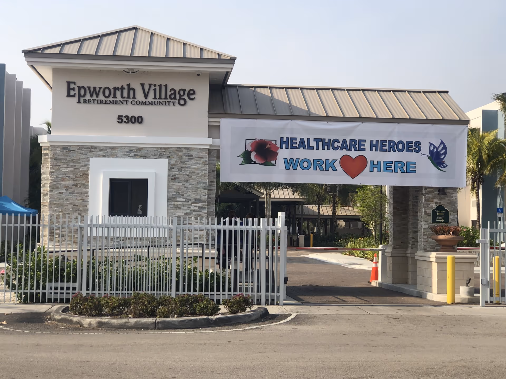 Exterior view of a senior living facility entrance with a banner and gate.