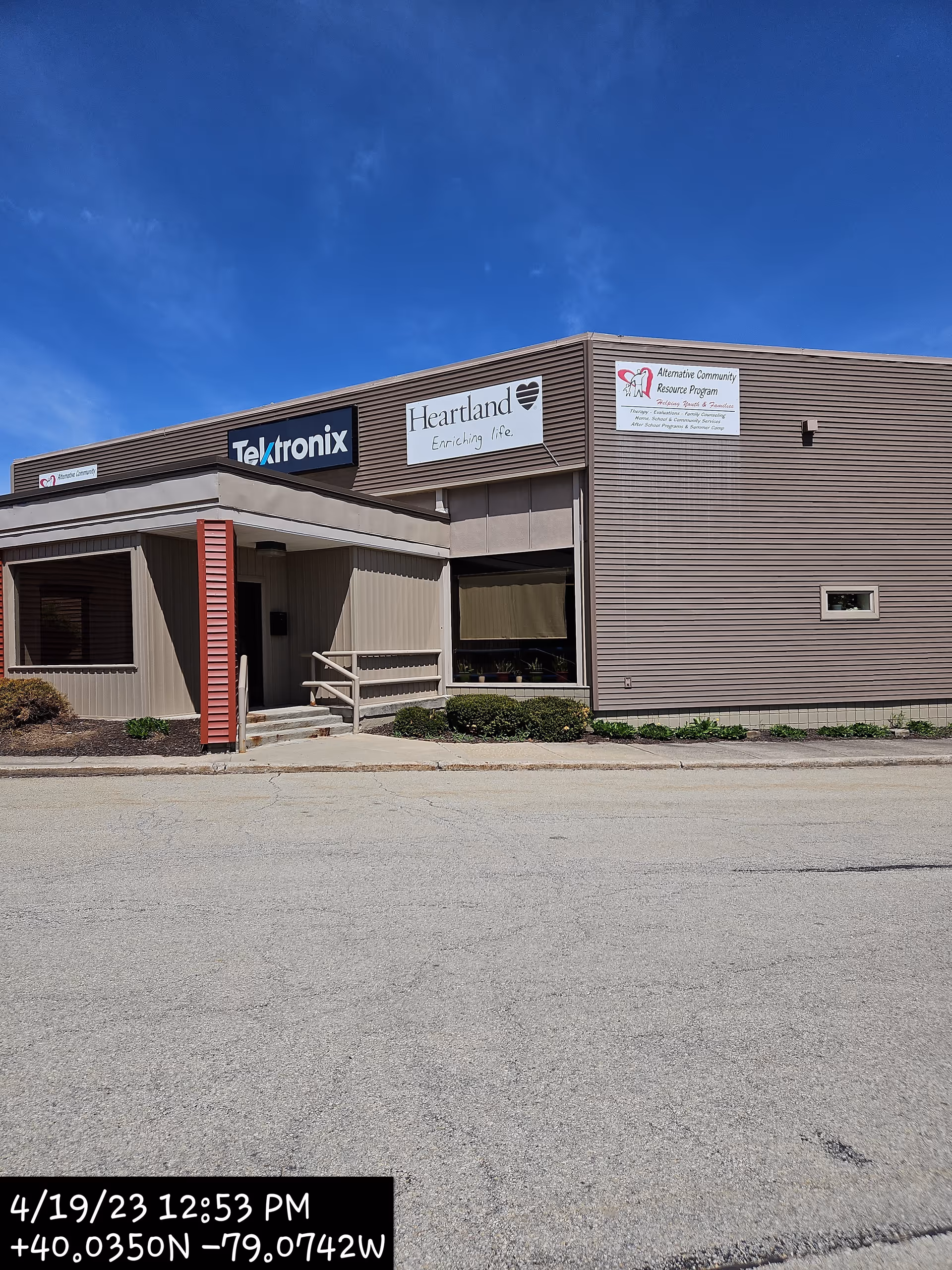 Front view of a Heartland Hospice building with signs under a blue sky.