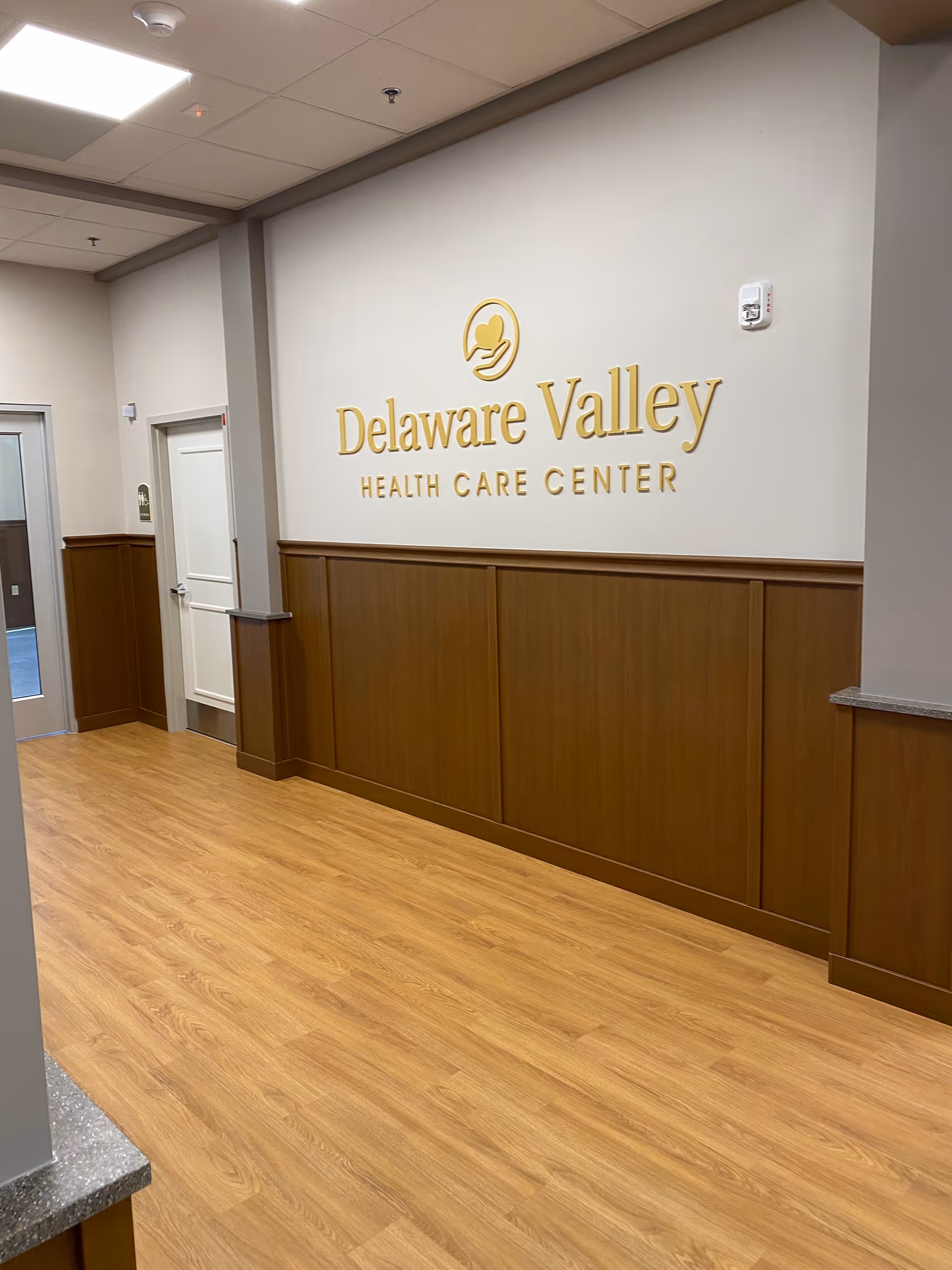 Interior hallway with wood wainscoting and a large Delaware Valley Health Care Center sign.
