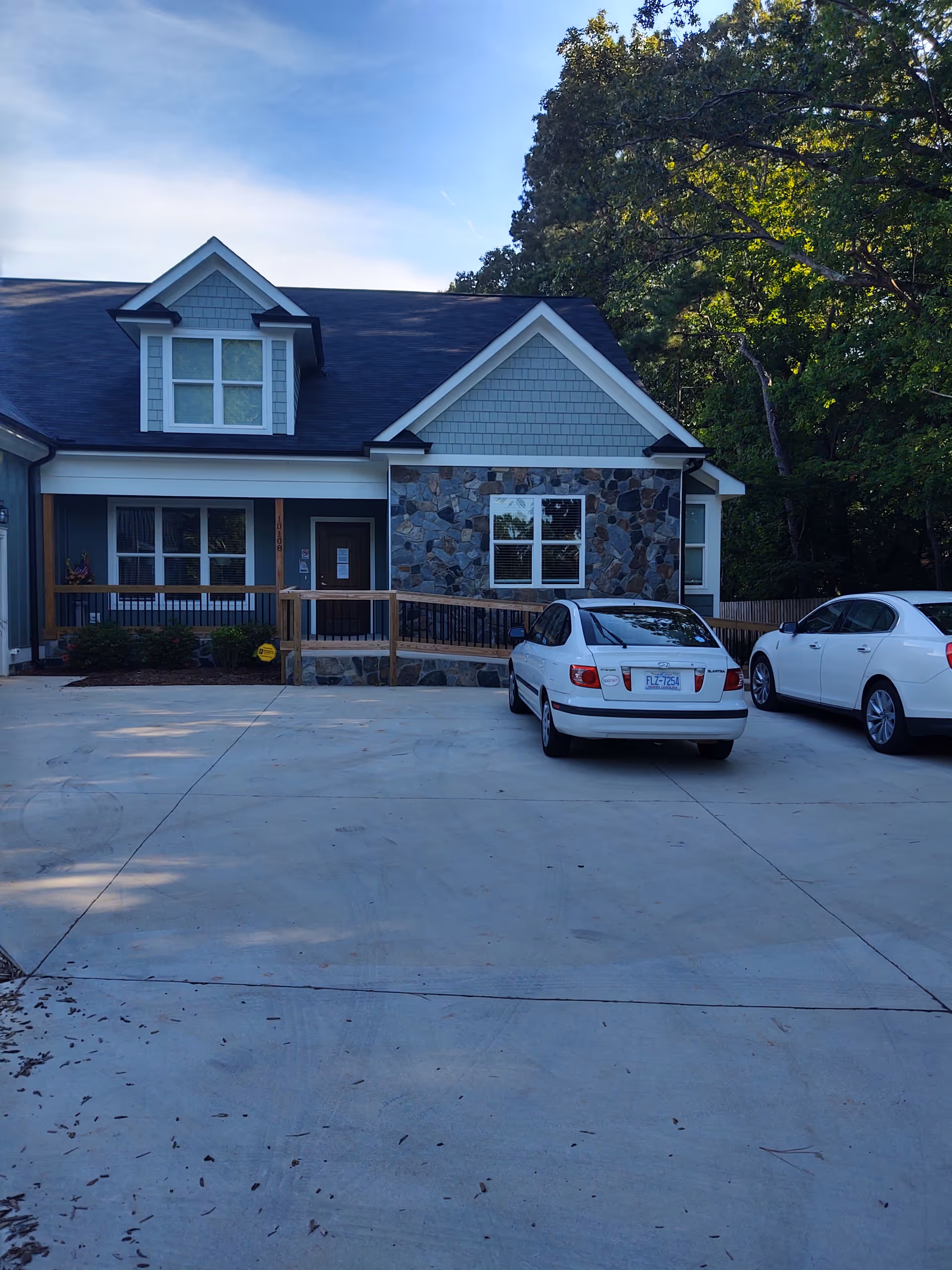 Front exterior of a modern senior living facility with stone accents and parked cars.