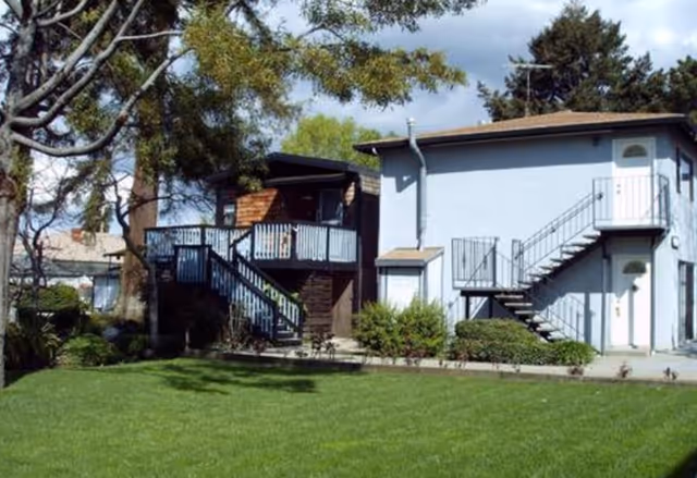 Exterior view of a Bethesda Home senior living building with staircases and a green lawn.