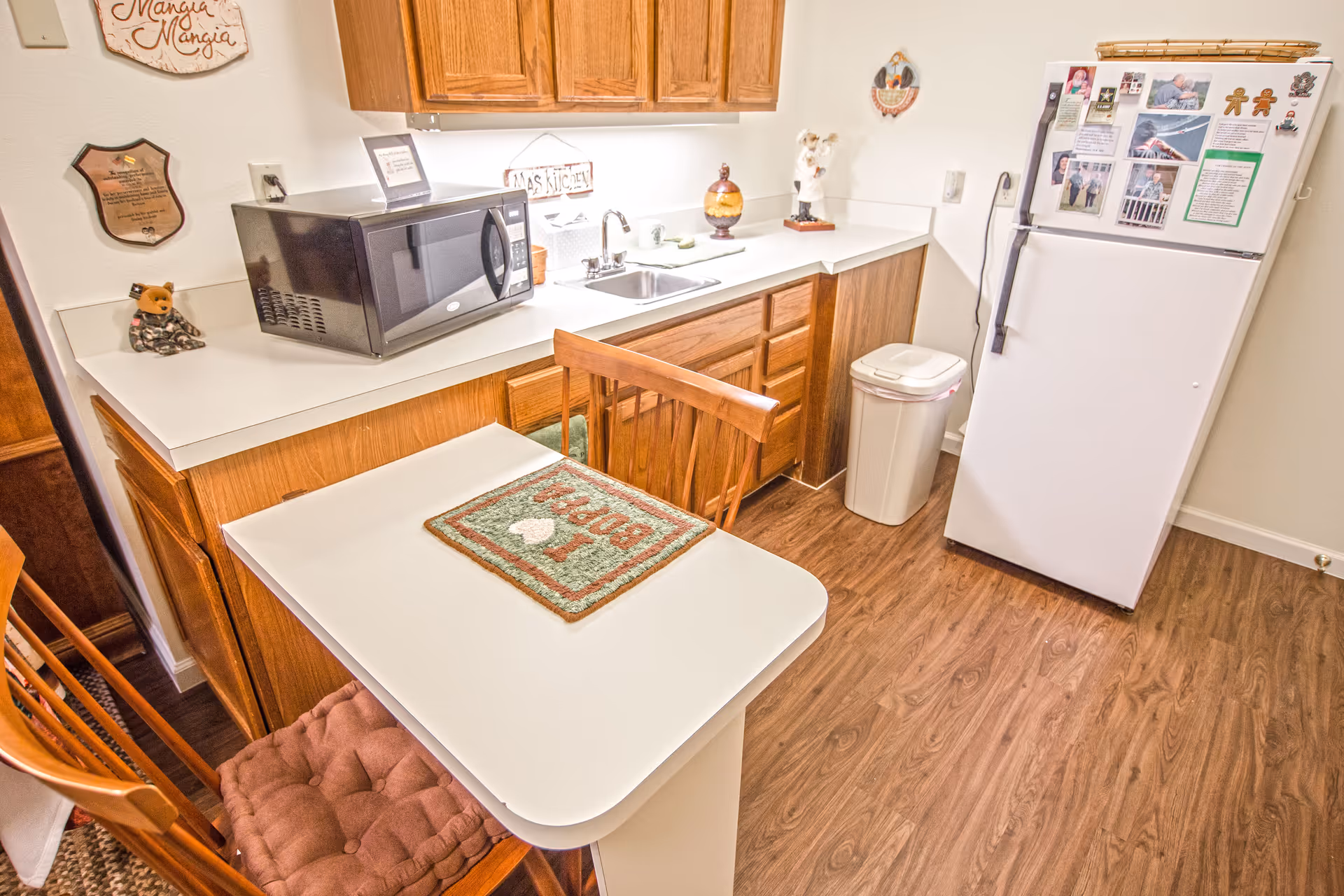 Compact kitchen in a senior living unit with fridge, microwave, sink, and table.