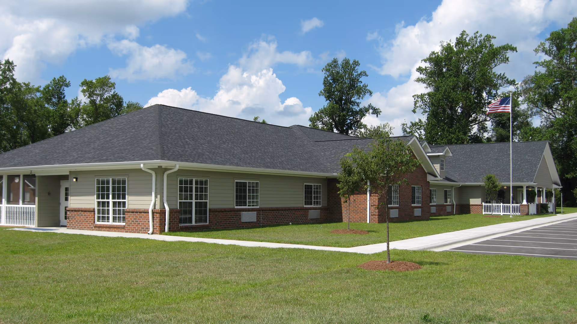 Single-story Edenton House facility with brick and siding exterior, parking lot, and flag.