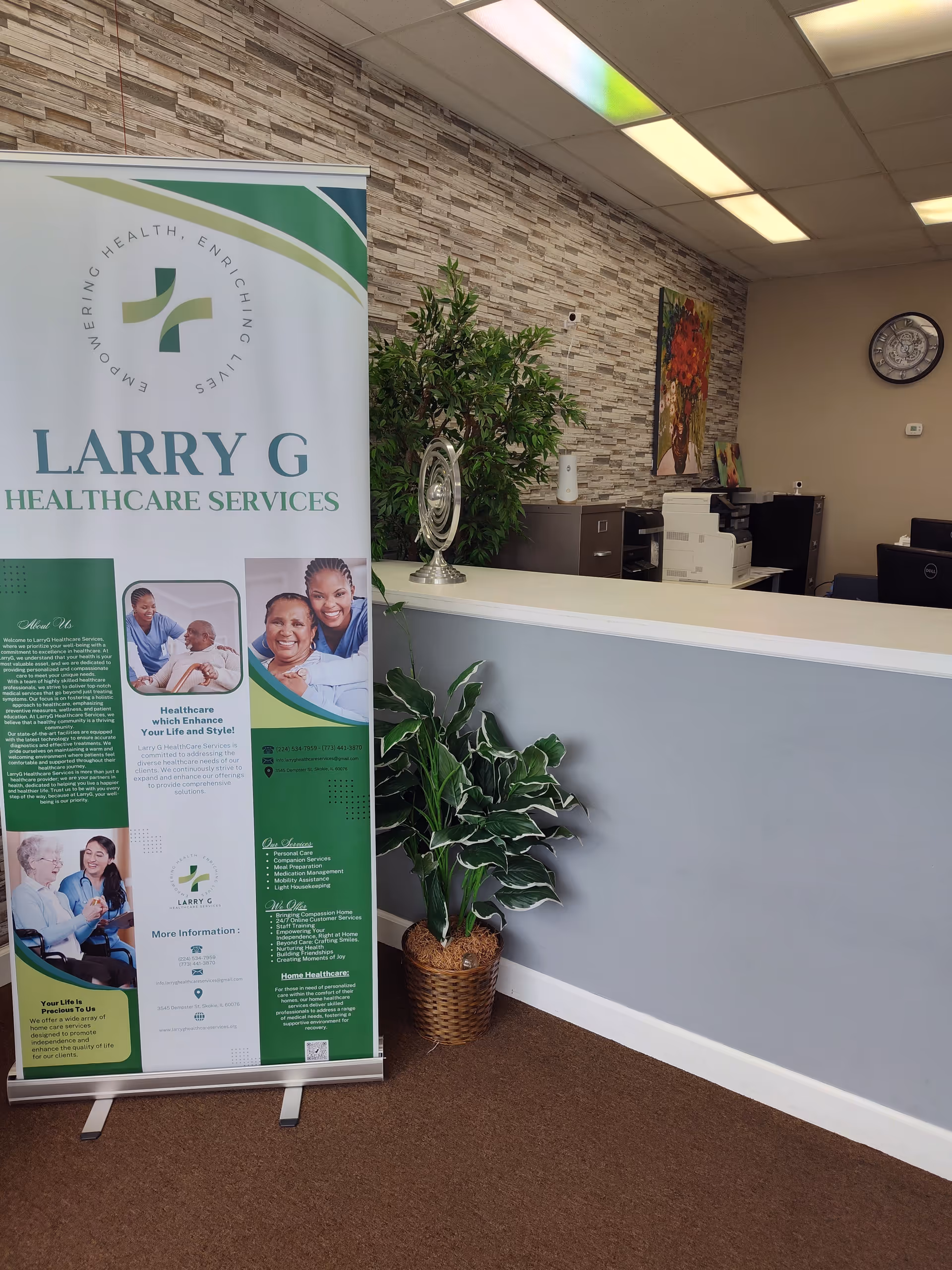 Reception area featuring a Larry G Healthcare Services banner, plants, and office equipment.