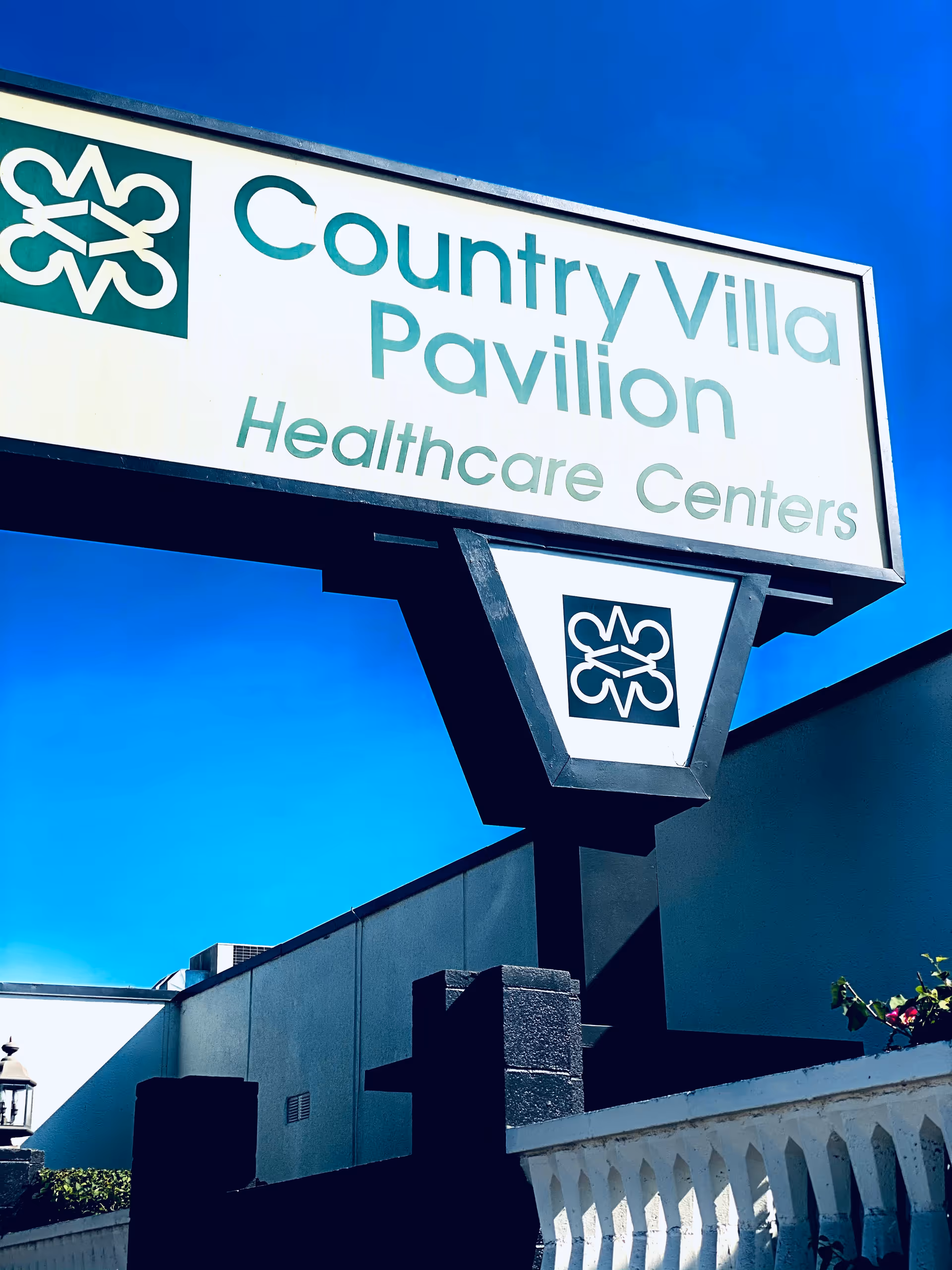 Exterior sign for Country Villa Pavilion Healthcare Centers against a clear blue sky.