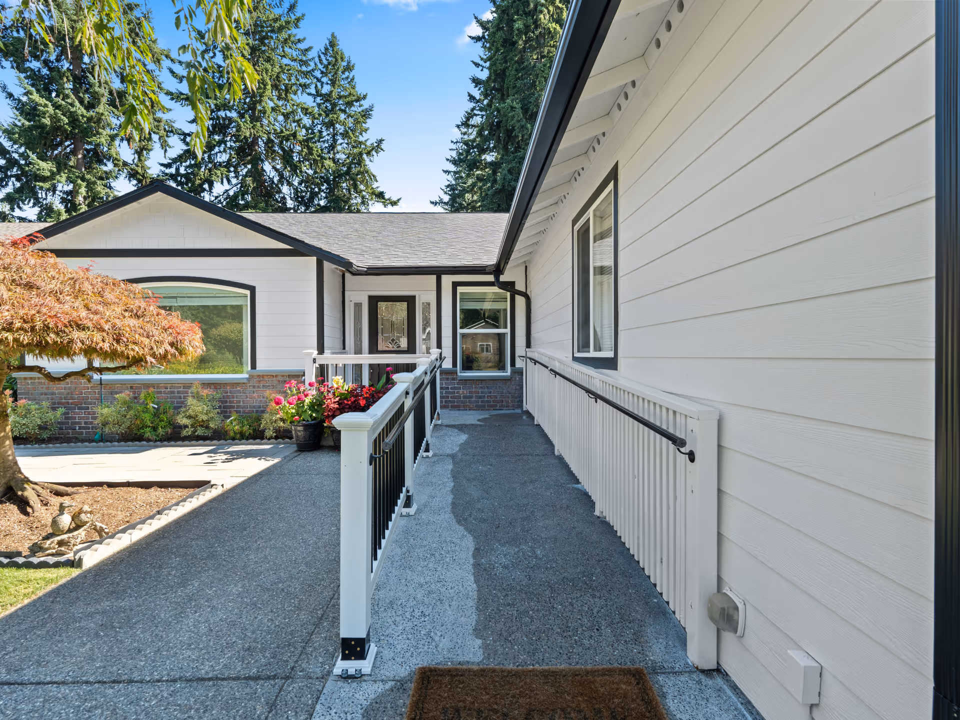 Exterior view of a senior living facility with a ramp, walkway, and potted plants.