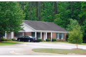 Front view of The Columbia Presbyterian Community facility with a parked car and trees.