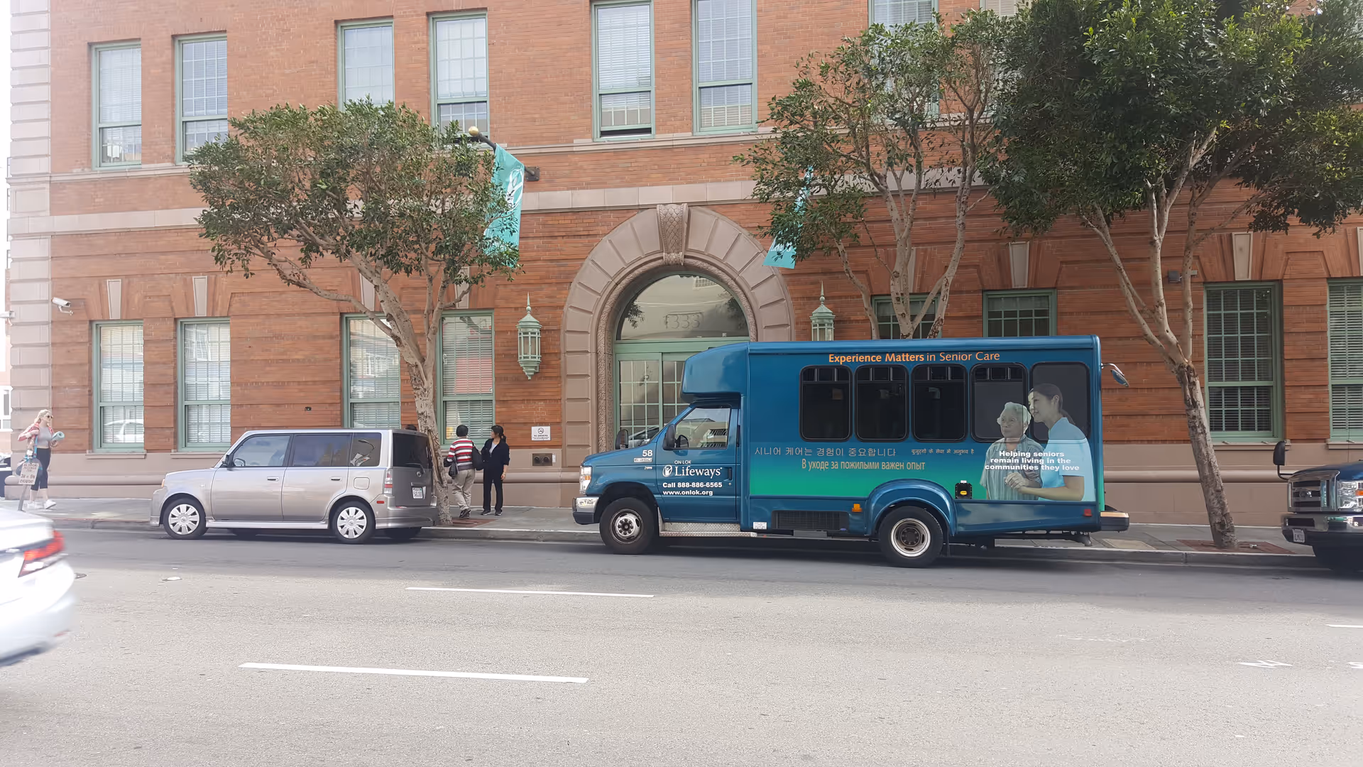Blue shuttle bus in front of brick building with arched entrance.