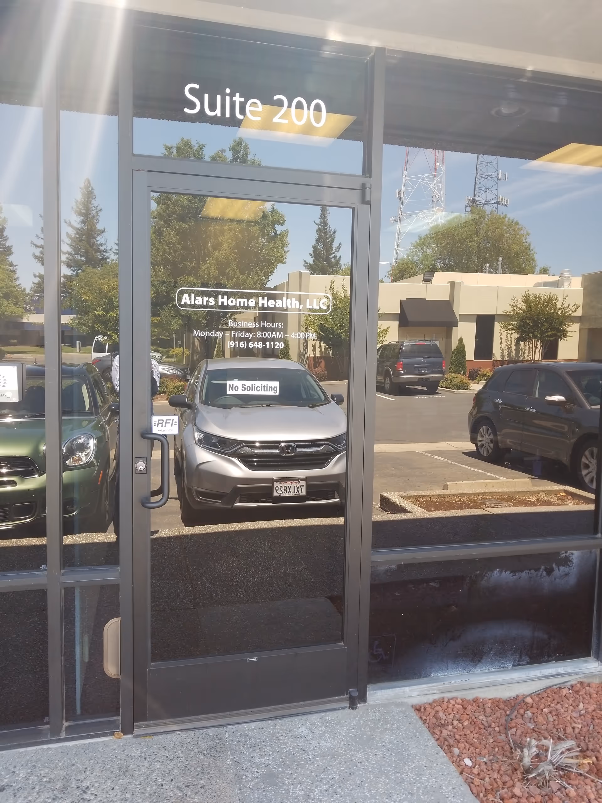 Glass storefront entrance reads Suite 200 for Alars Home Health, LLC, in a parking lot.