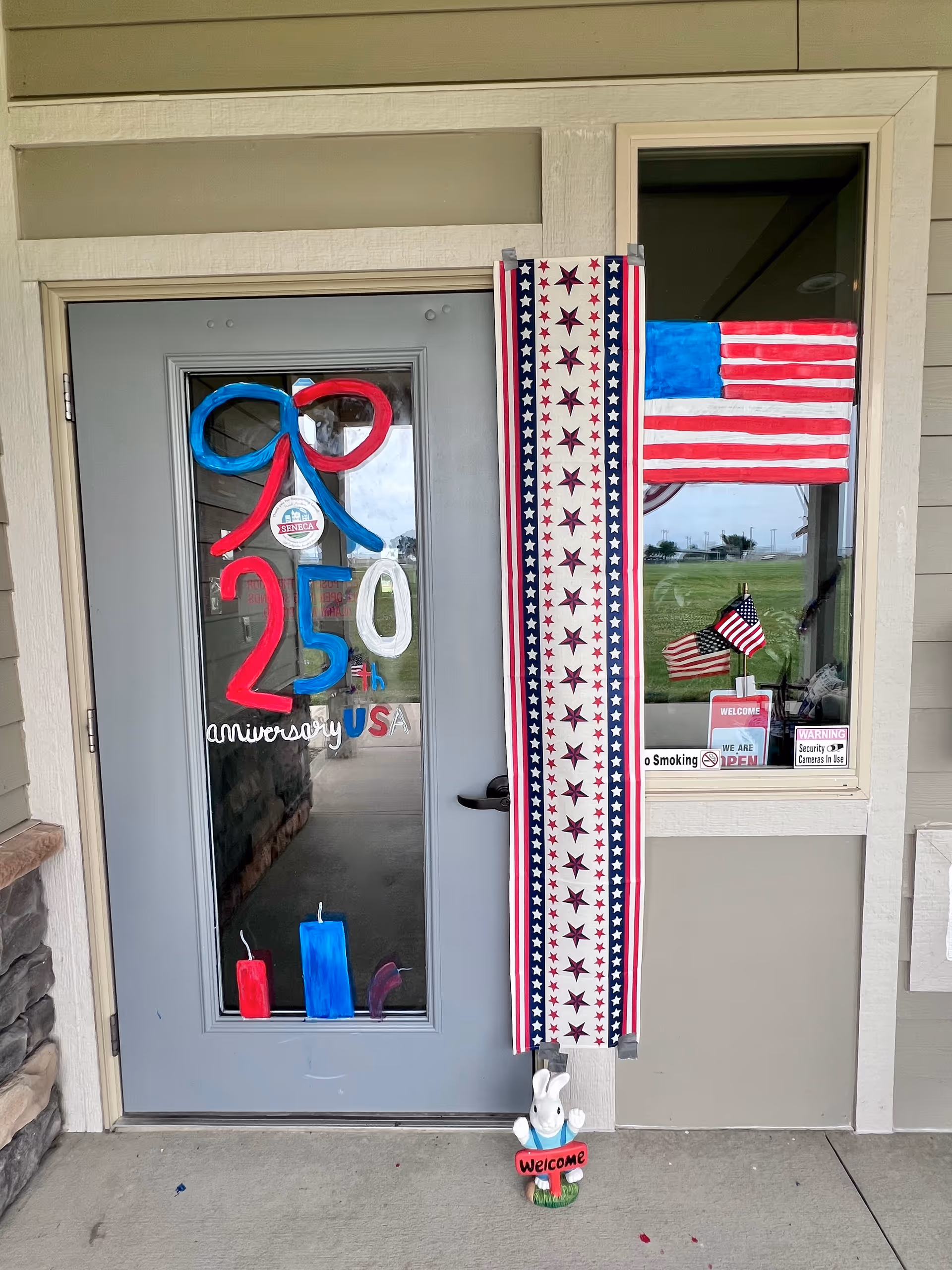 Decorated building entrance with patriotic banners and anniversary signage at Oakley Place of Seneca