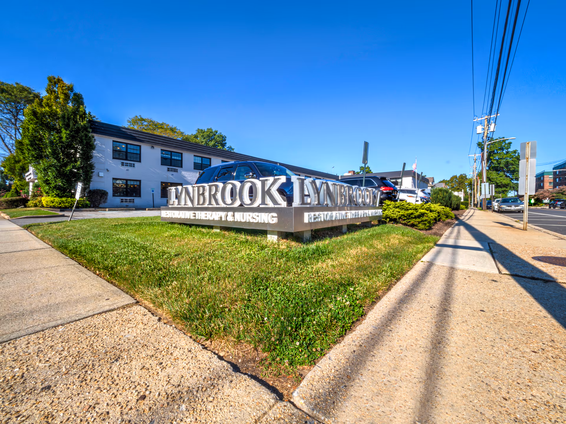 Exterior of Lynbrook Restorative Therapy and Nursing building with prominent sign on lawn.