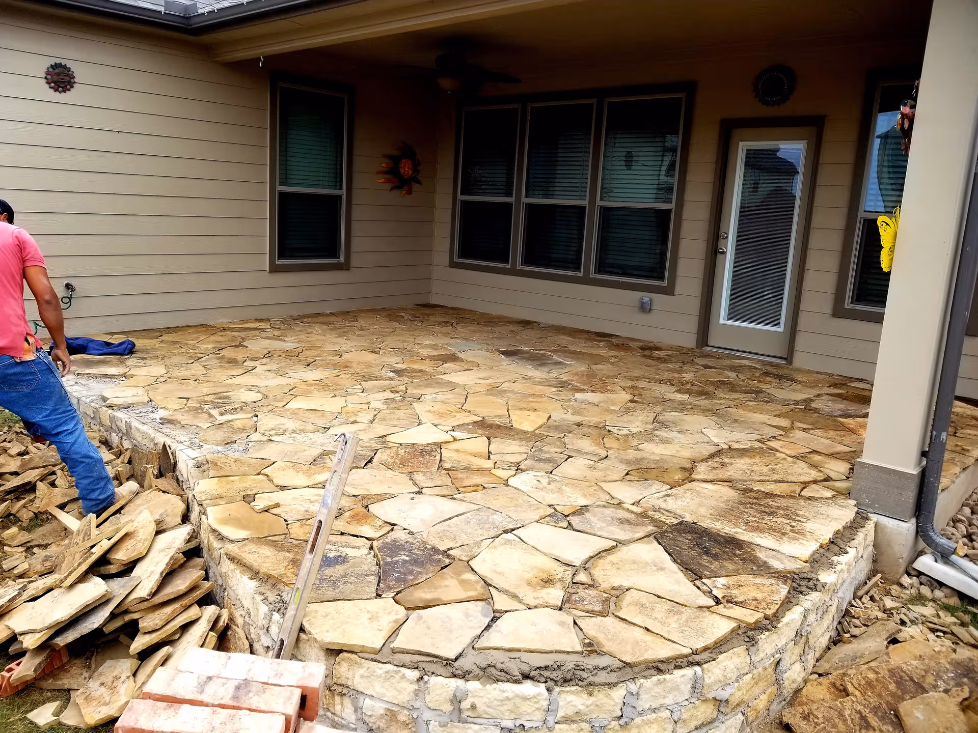 Stone patio under construction outside a beige senior living building with windows and door.
