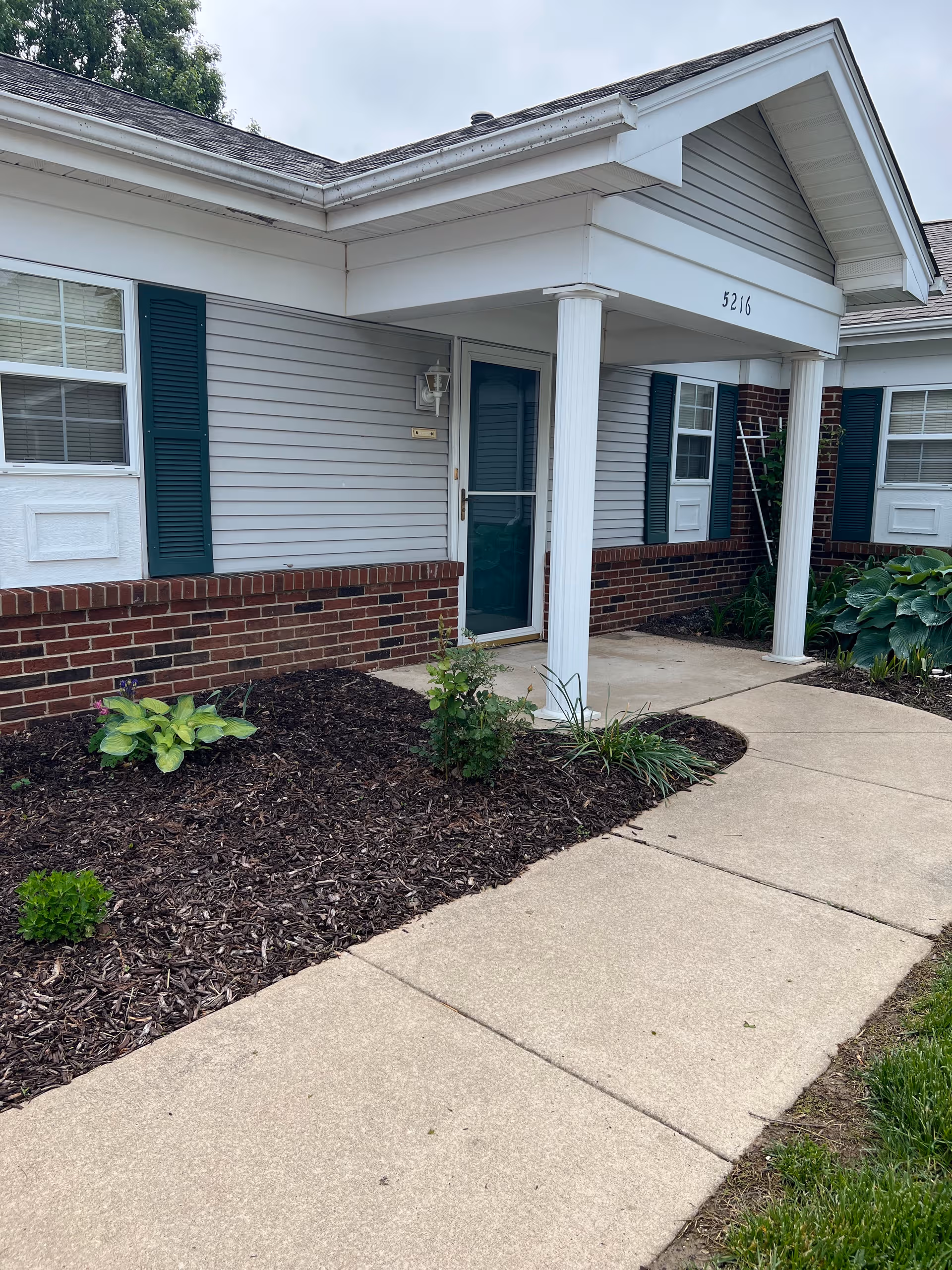 Exterior view of Asbury Village front entrance with a walkway and landscaping.