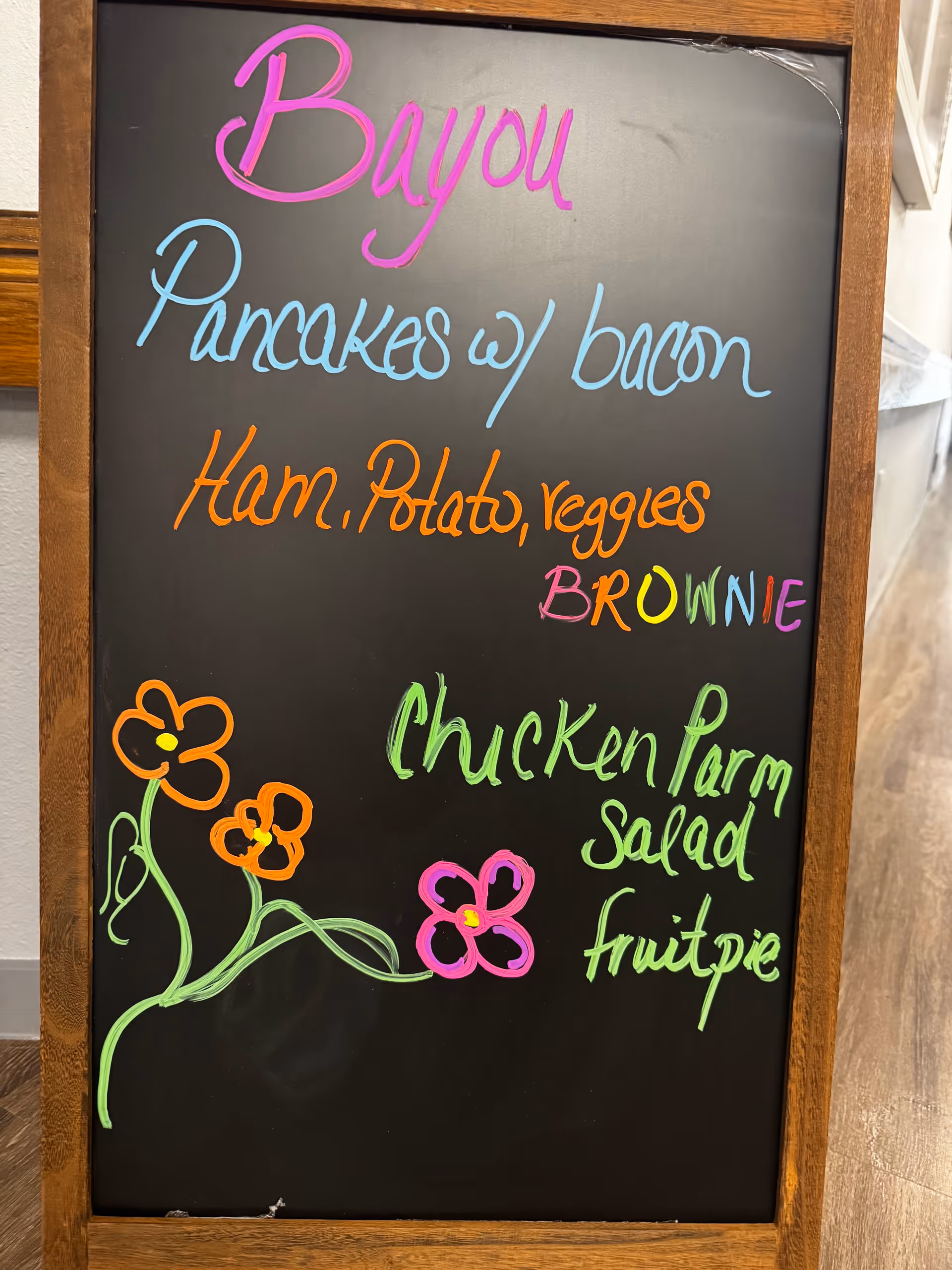 Colorful chalkboard menu listing meals inside Bayou Palms Assisted Living dining area.