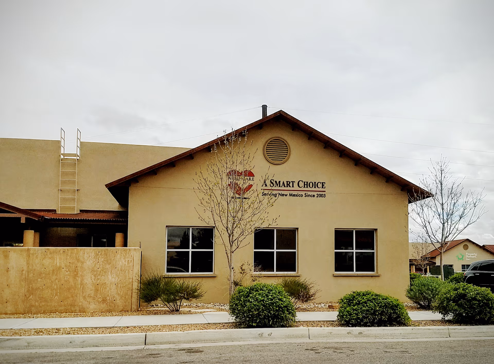 Beige single-story building with peaked roof, two windows, landscaping; Smart Choice sign visible.