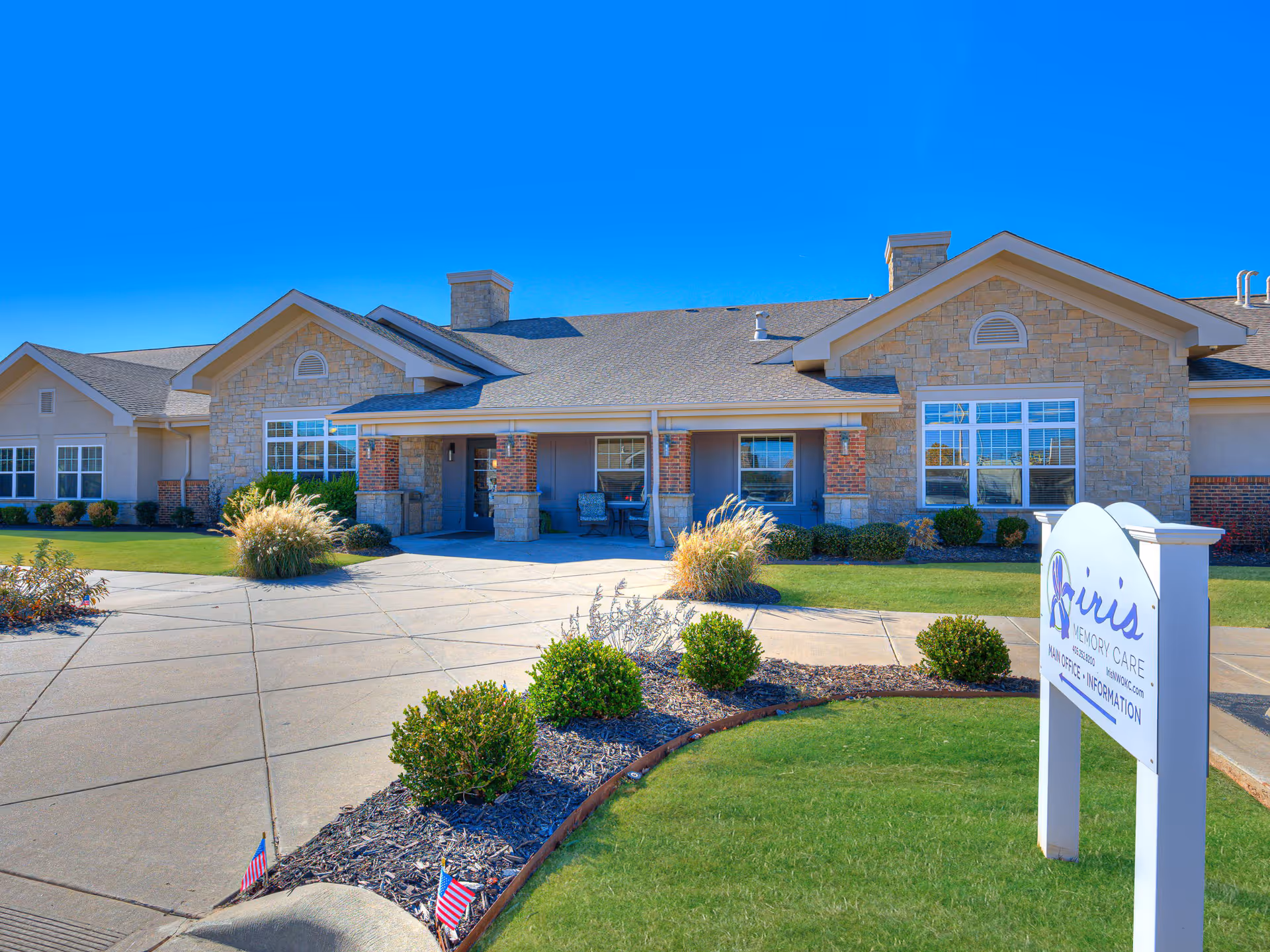 Front exterior of Iris Memory Care facility in NW Oklahoma City with manicured yard and sign.