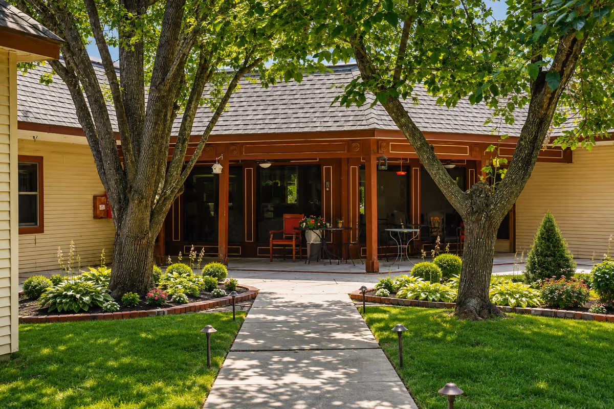 Entrance to Garden Court Health and Rehabilitation Center with a shaded porch and landscaped garden.