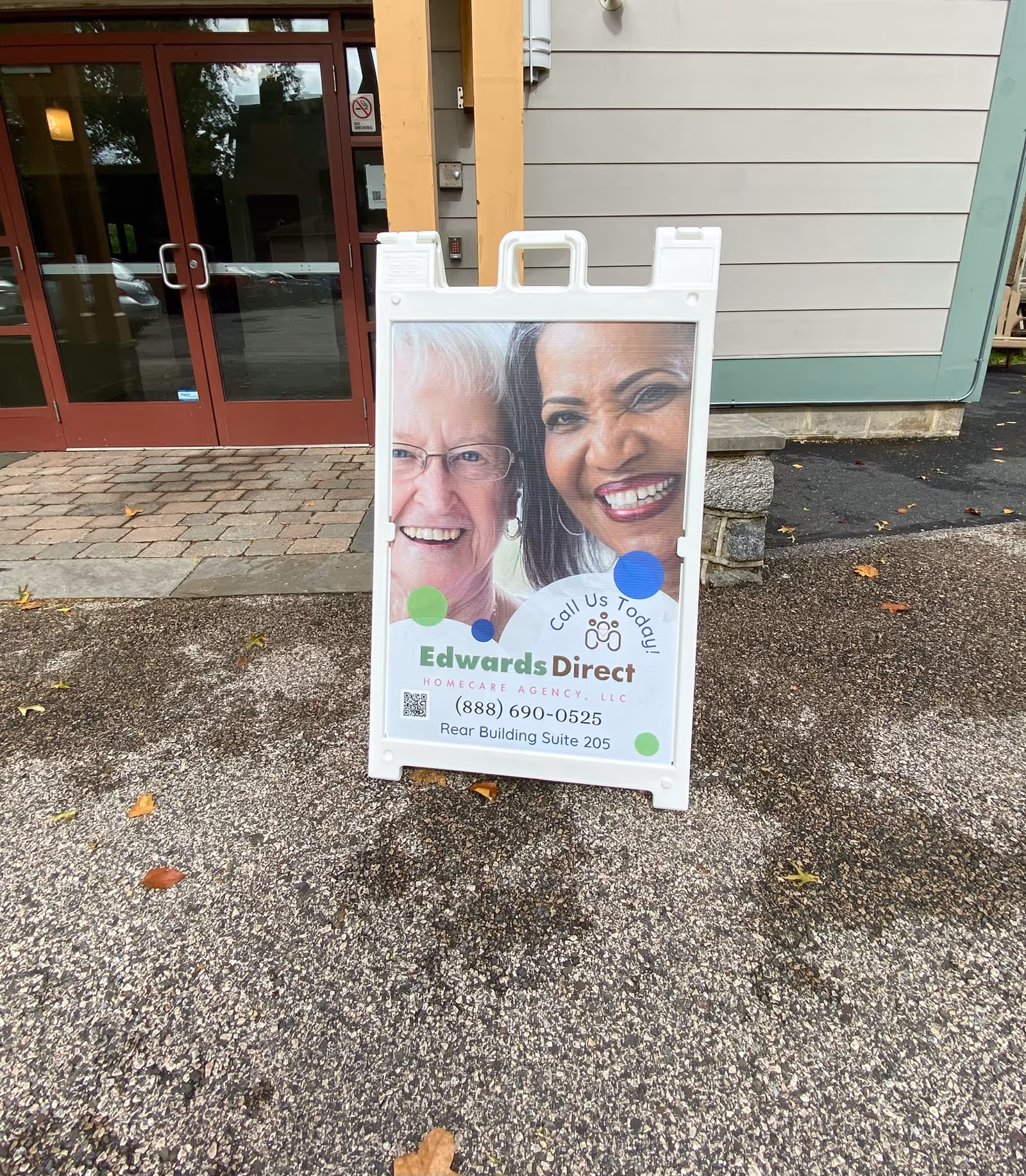Outdoor signboard advertising Edwards Direct Home Care Agency in front of building entrance