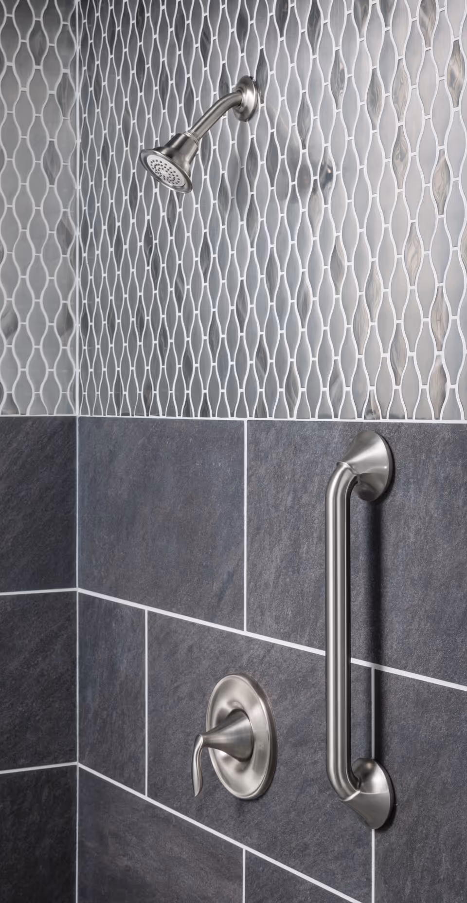 Handheld showerhead and metal grab bar mounted on a tiled bathroom wall.