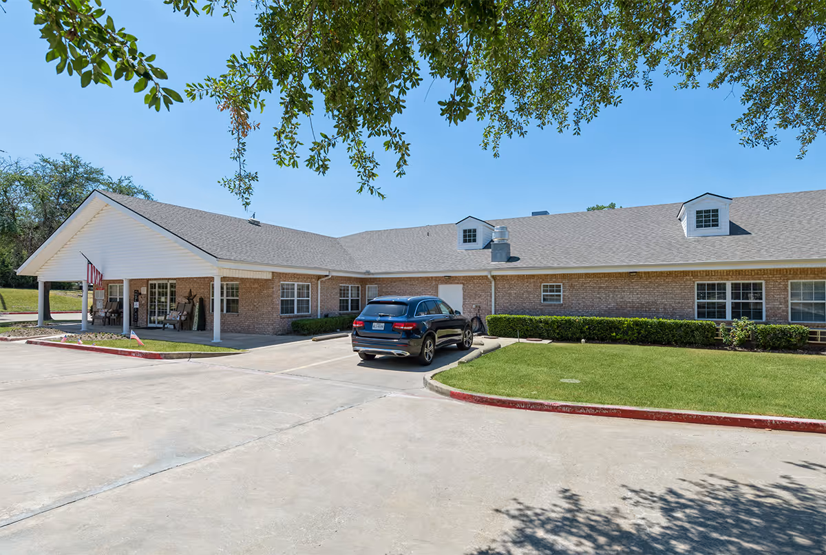 Single-story brick senior living facility with a covered entrance and parked car.