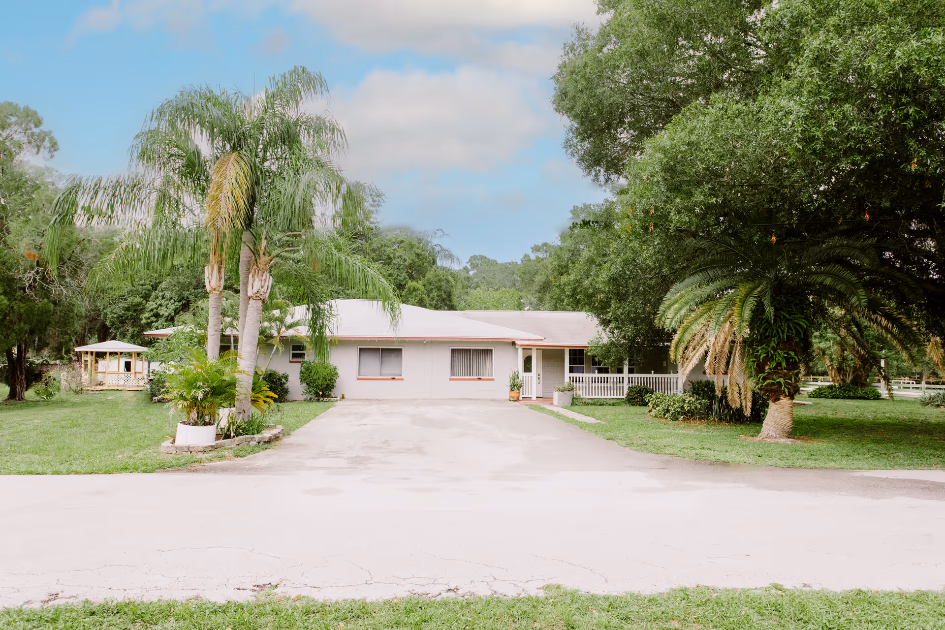 Exterior view of Lantern Senior Care facility with a driveway and trees.