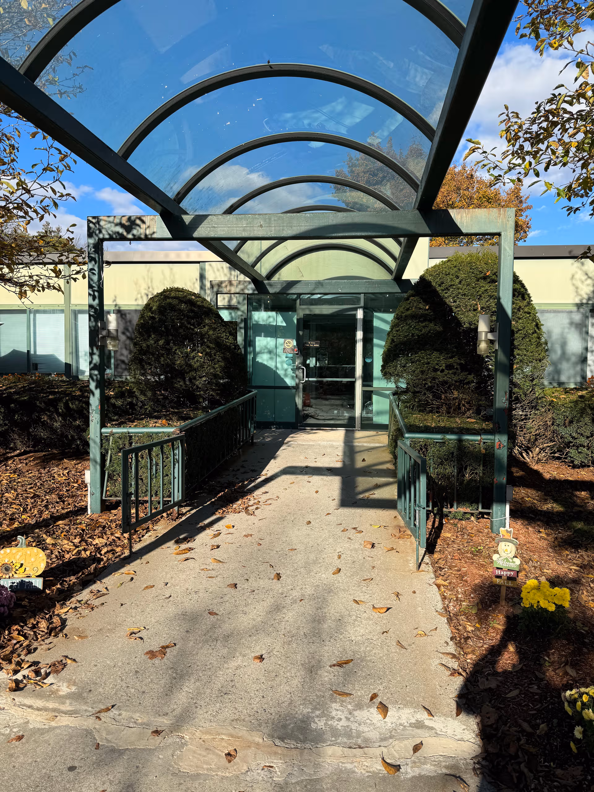 Glass-covered walkway leads to River Terrace entrance flanked by shrubs.