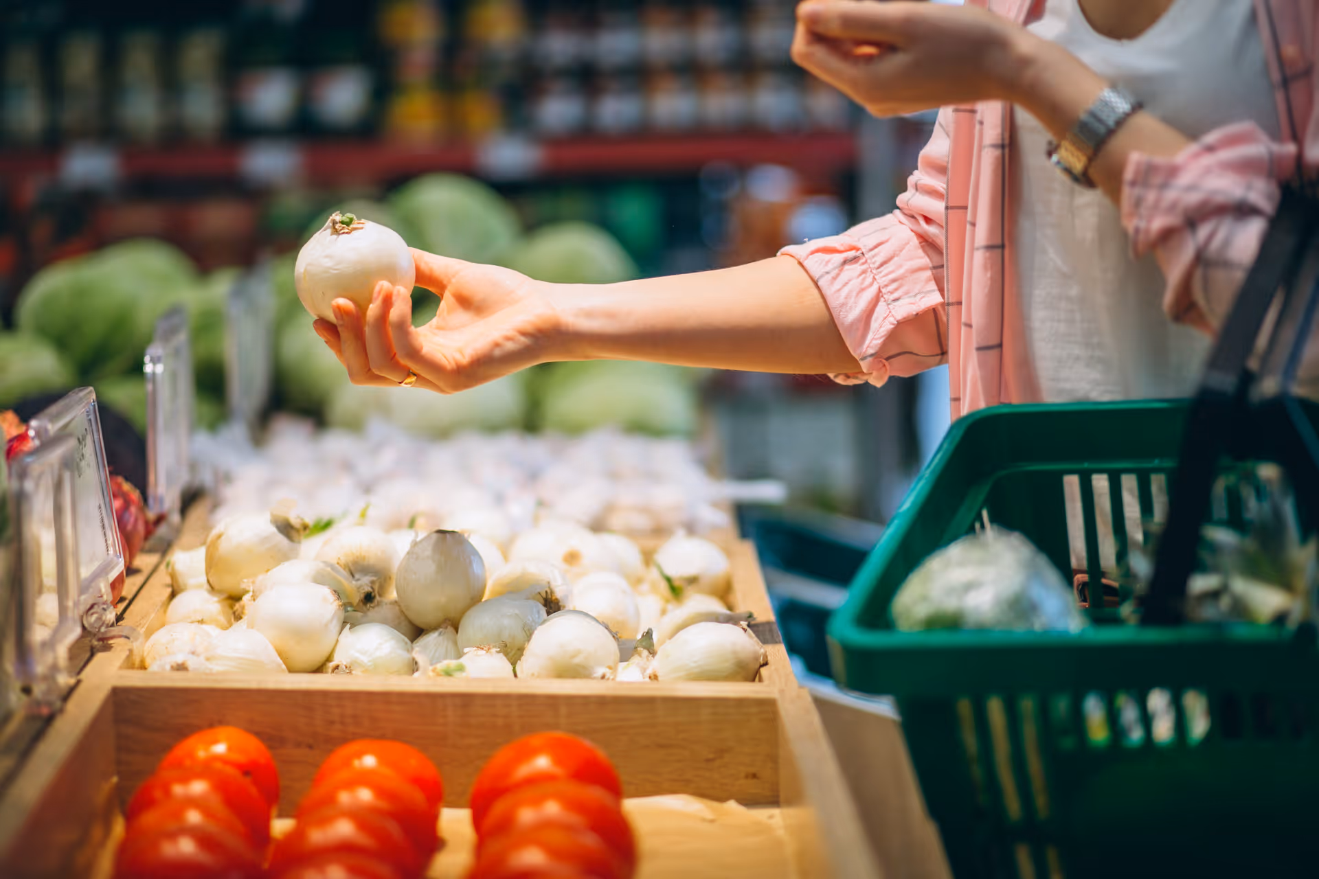 A shopper holds a white onion at a bright indoor produce display.