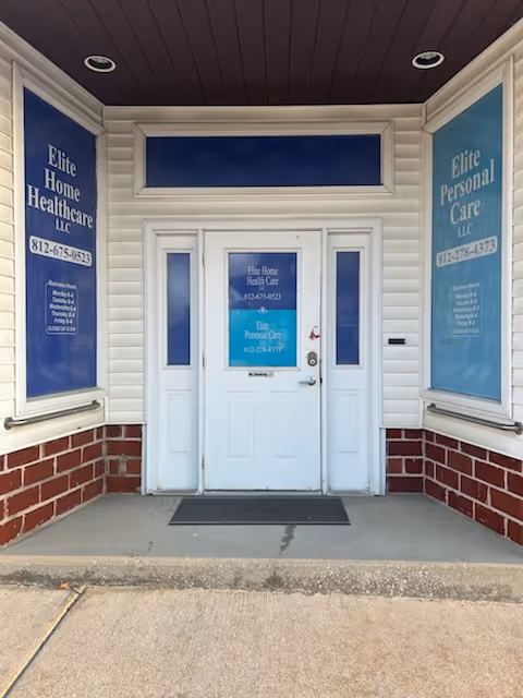Entrance to Elite Personal Care LLC building with white door and blue banners.