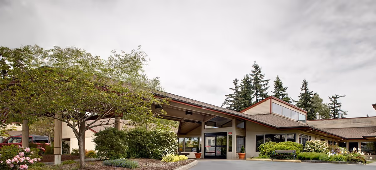 Exterior view of Avalon Healthcare in Bellingham with a glass entrance and landscaping.
