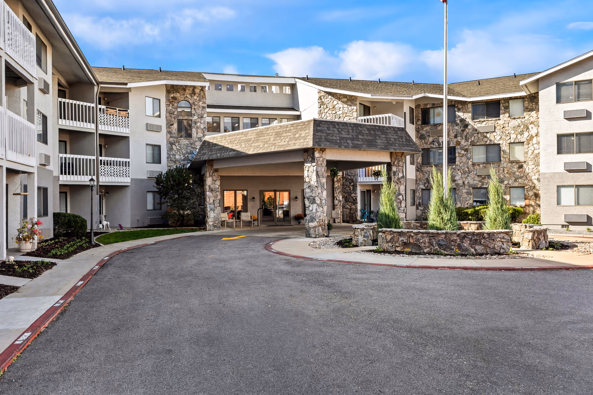 Exterior view of Harrison Regent Retirement Community with stone entrance and circular driveway.