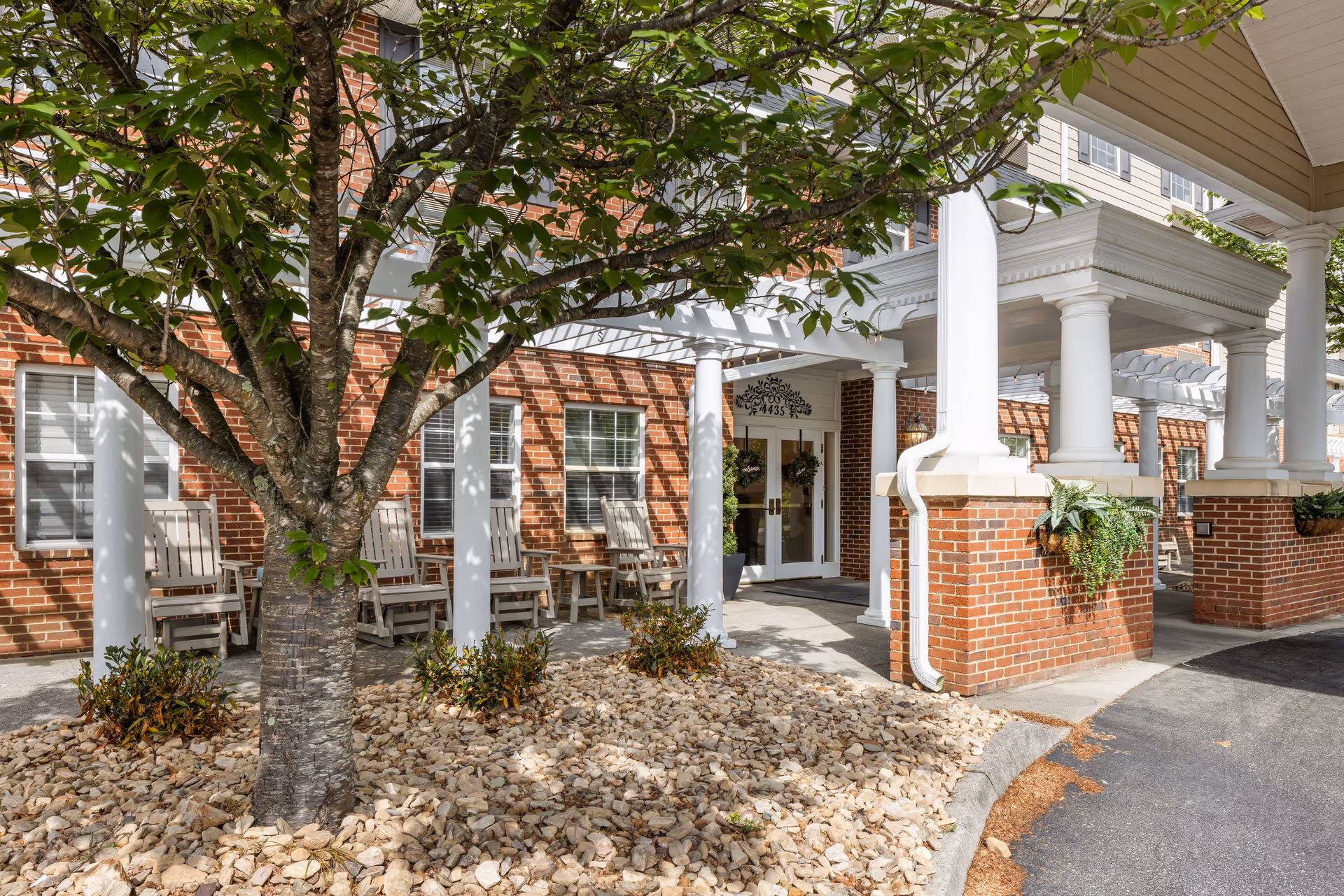Exterior entrance of TerraBella Pheasant Ridge with brick facade, white columns, and outdoor seating.