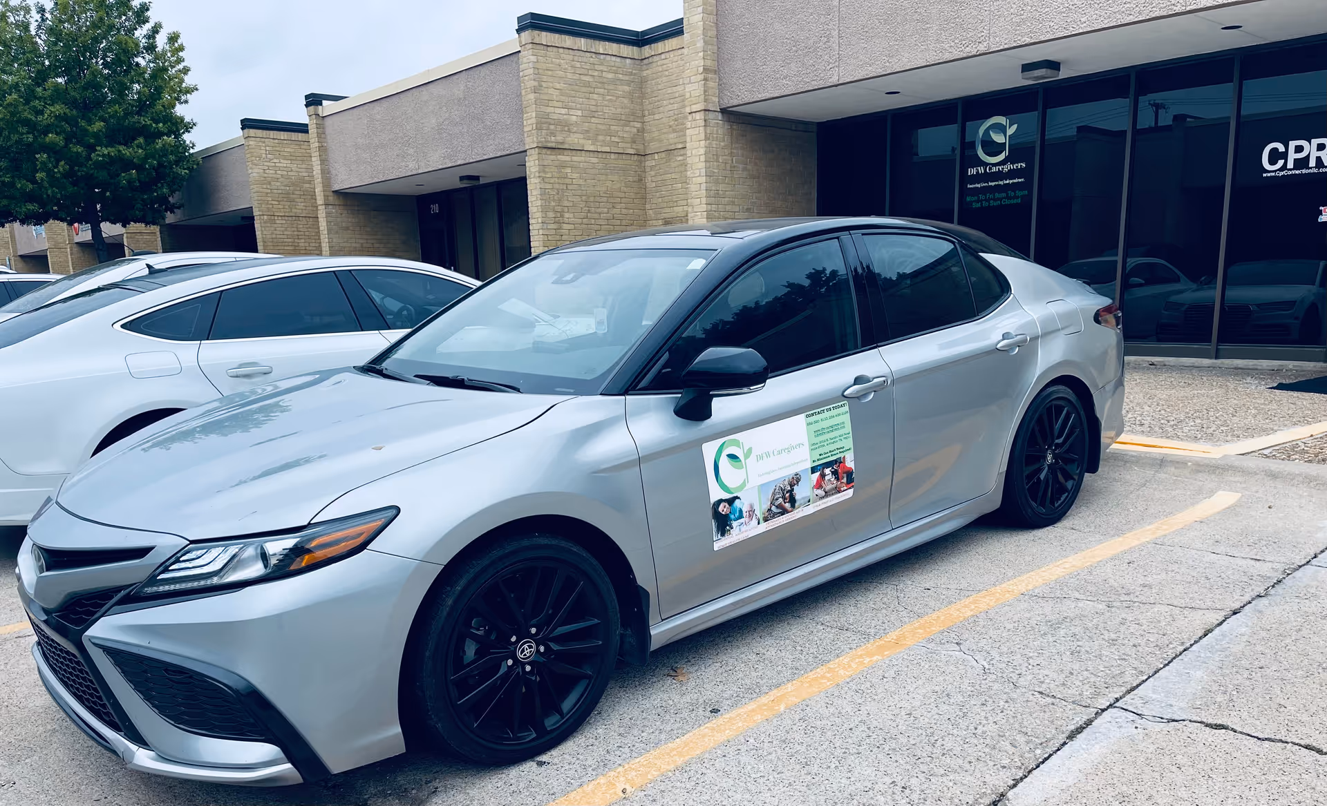 Two silver sedans parked in front of a DFW Caregivers storefront.