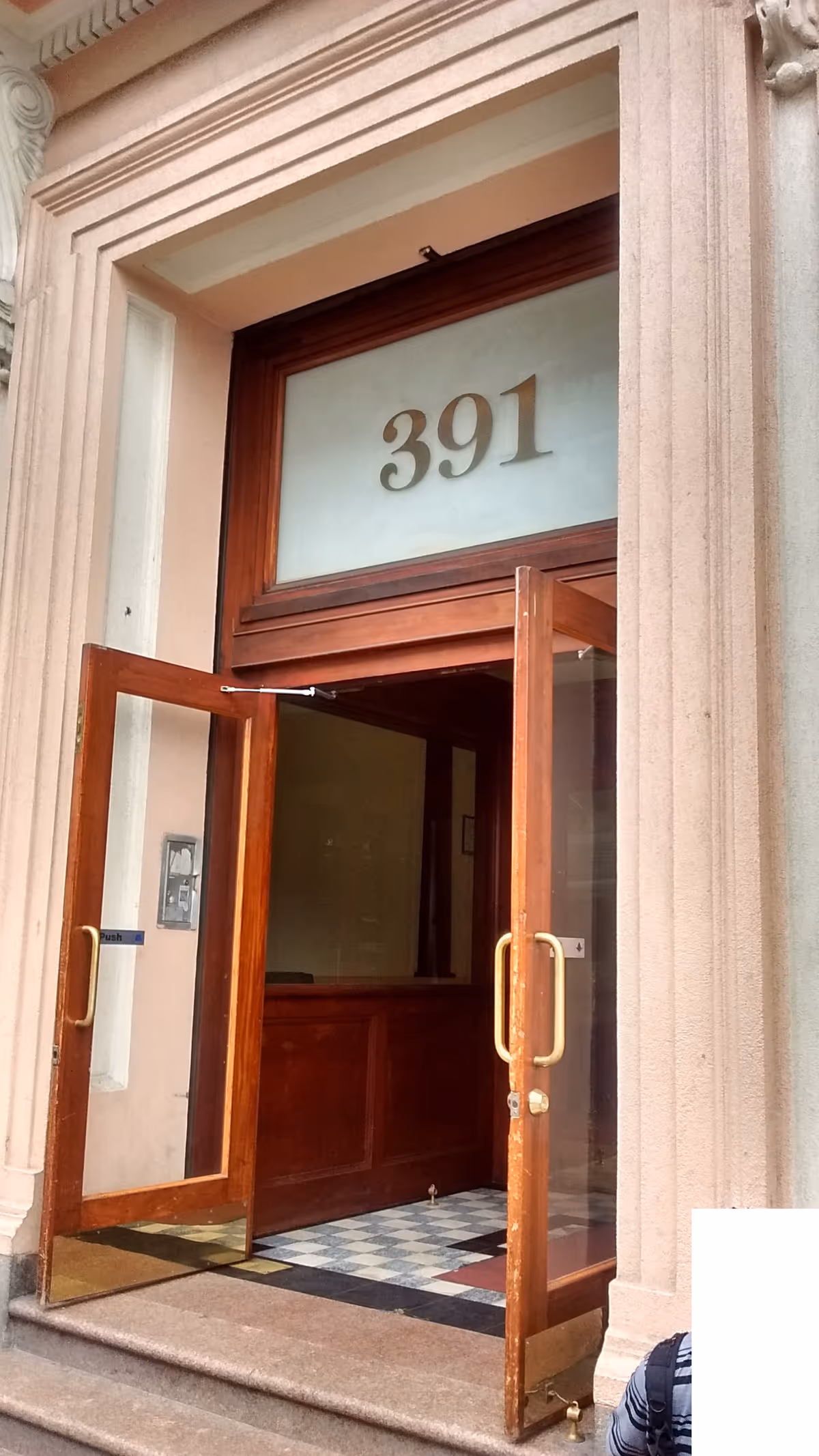 Open wooden doors show building entrance with the number 391 and tiled floor
